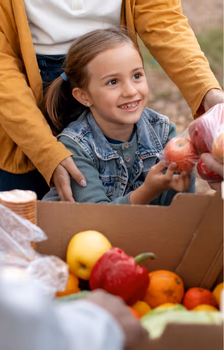 Niña que recibe una bolsa de manzanas como donación