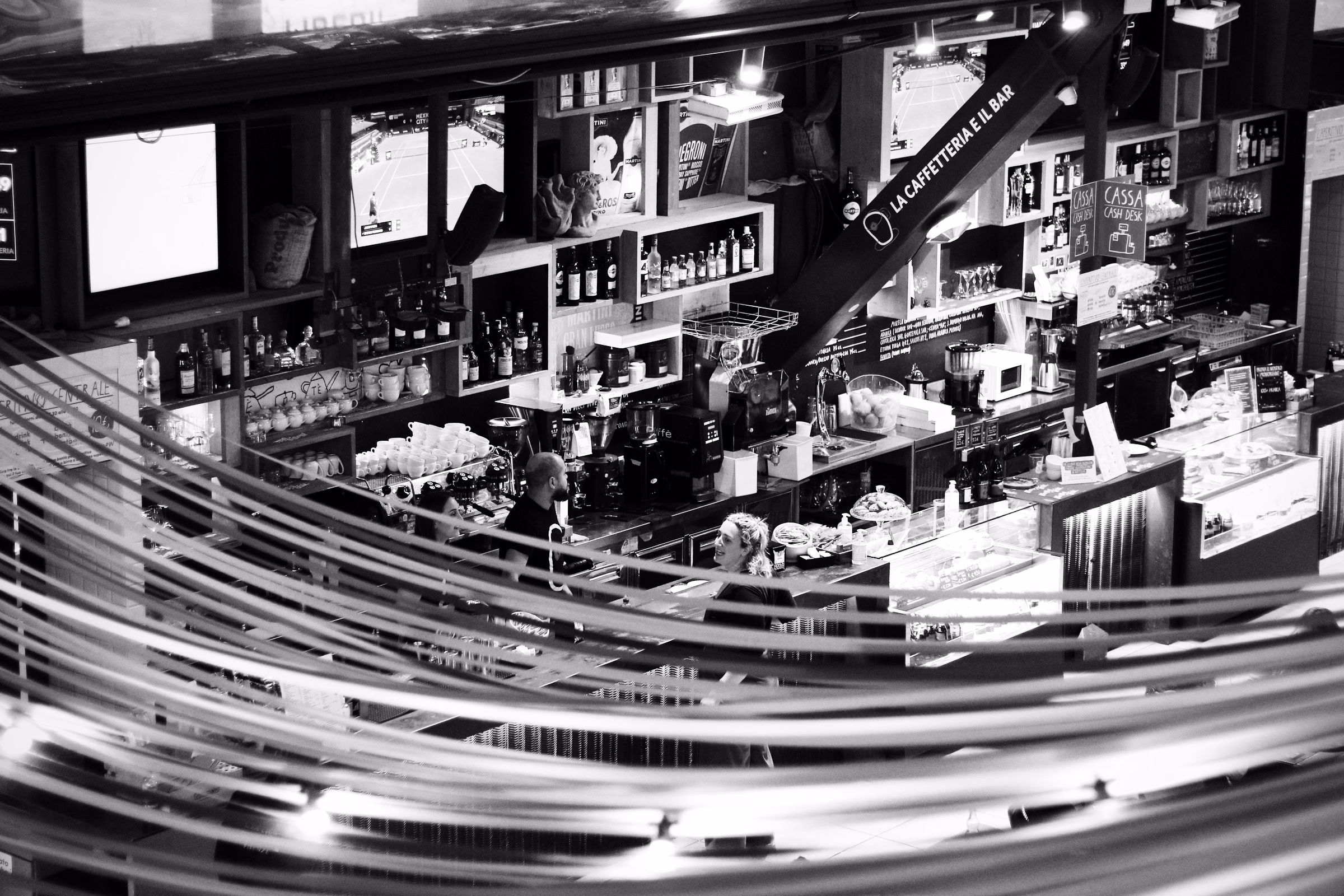 A cafe bar seen from above with light trails sweeping along the counter, in black and white