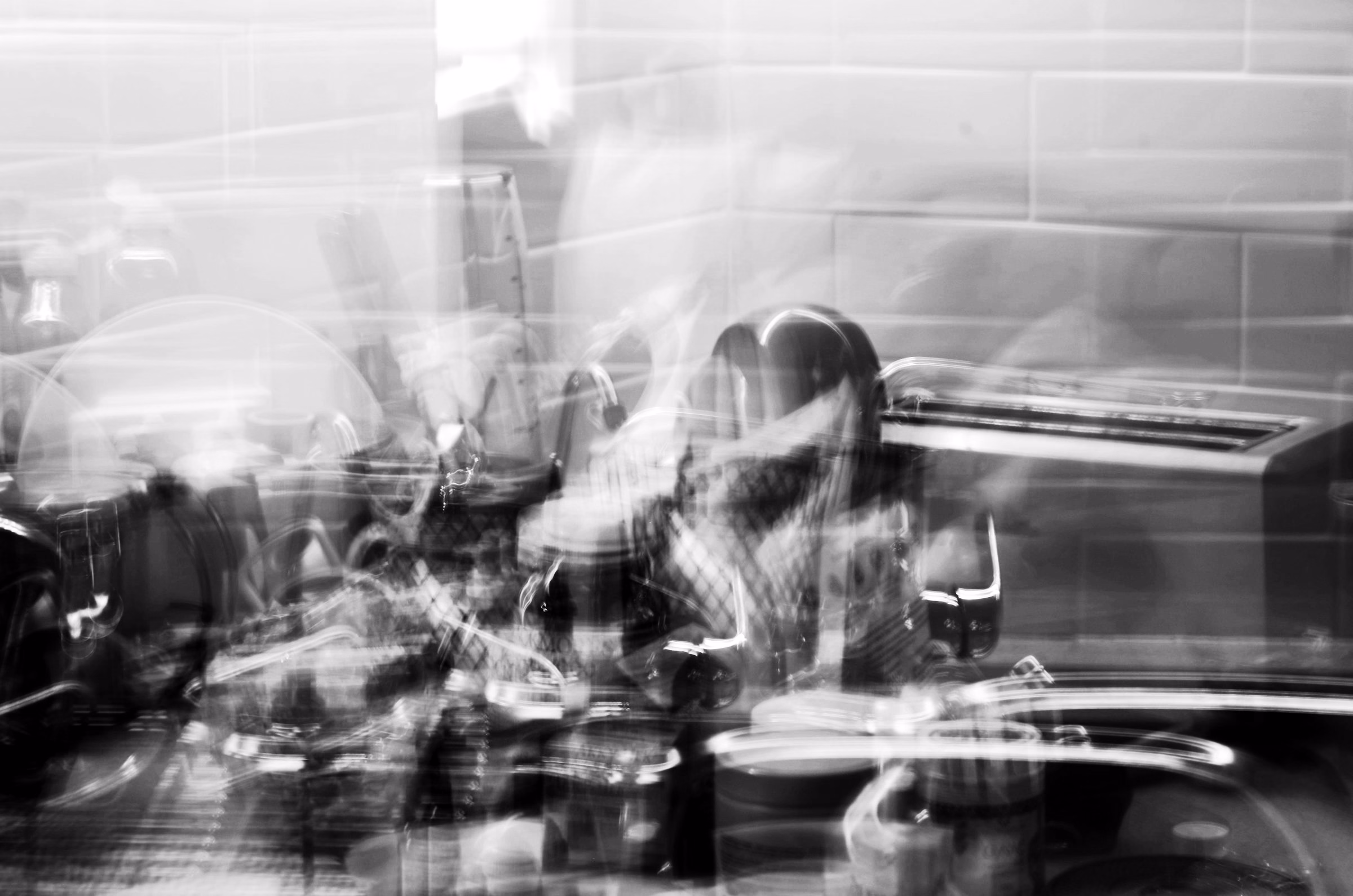 A group of diners at a full table, blurred with movement, in black and white