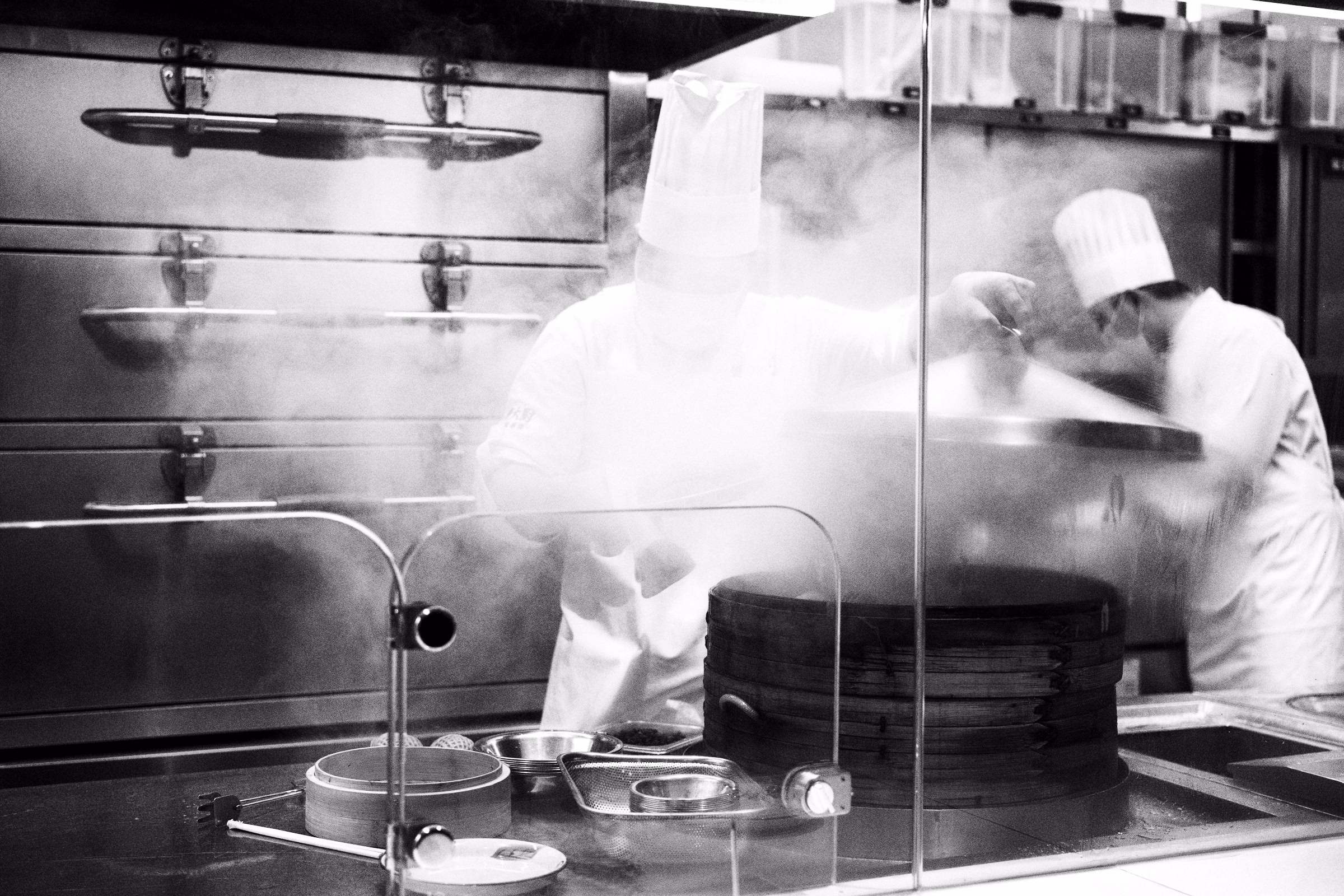 Chefs working through clouds of steam in a professional kitchen, in black and white