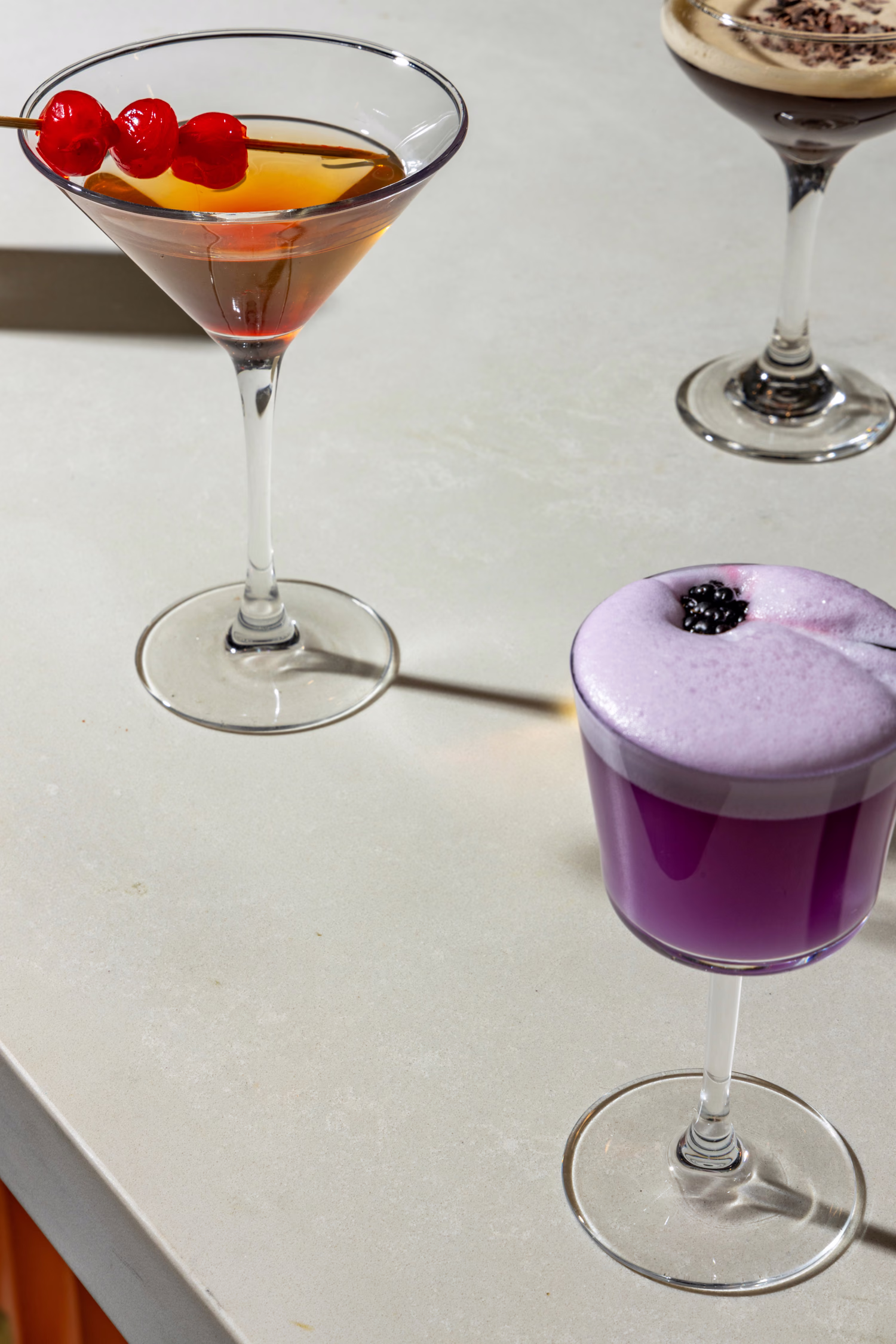 Three cocktails on a pale stone bar at Mistora