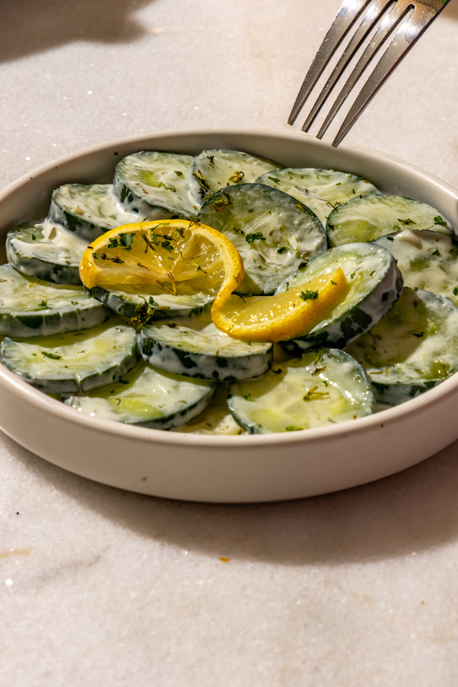 Cucumber salad in a creamy herb dressing with lemon slices at Mistora