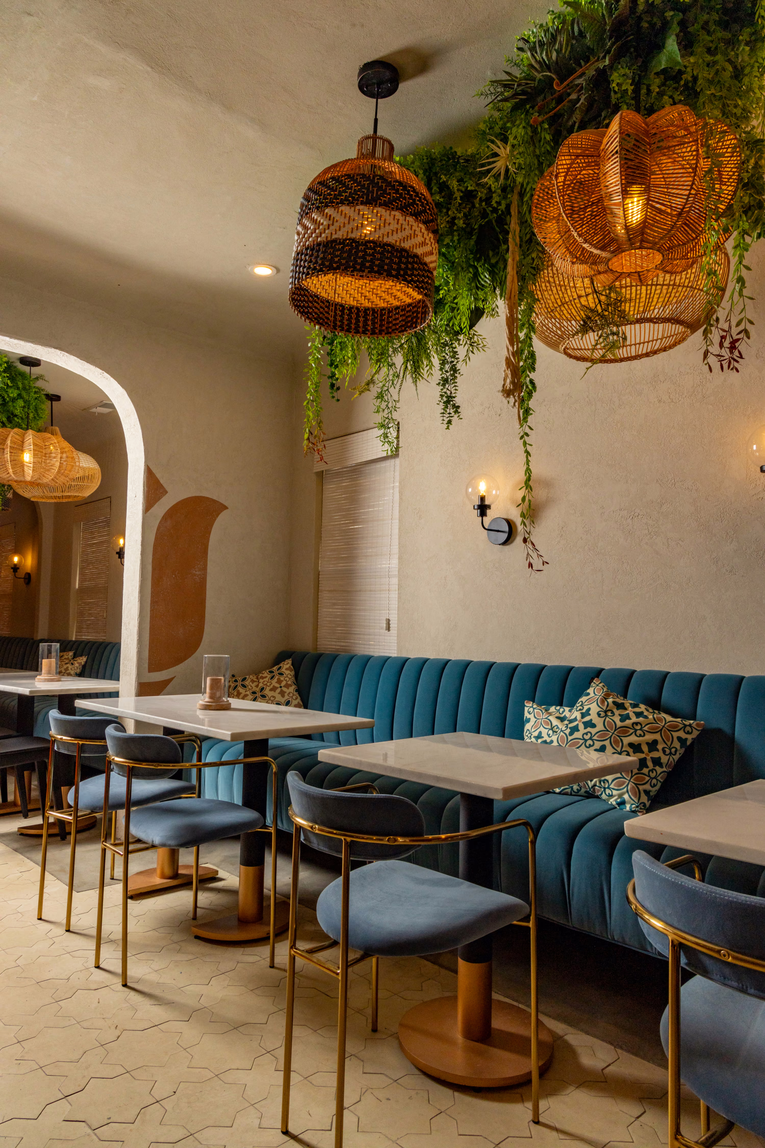 Mistora's dining room, with a blue banquette, pale stone tables and woven pendant lights