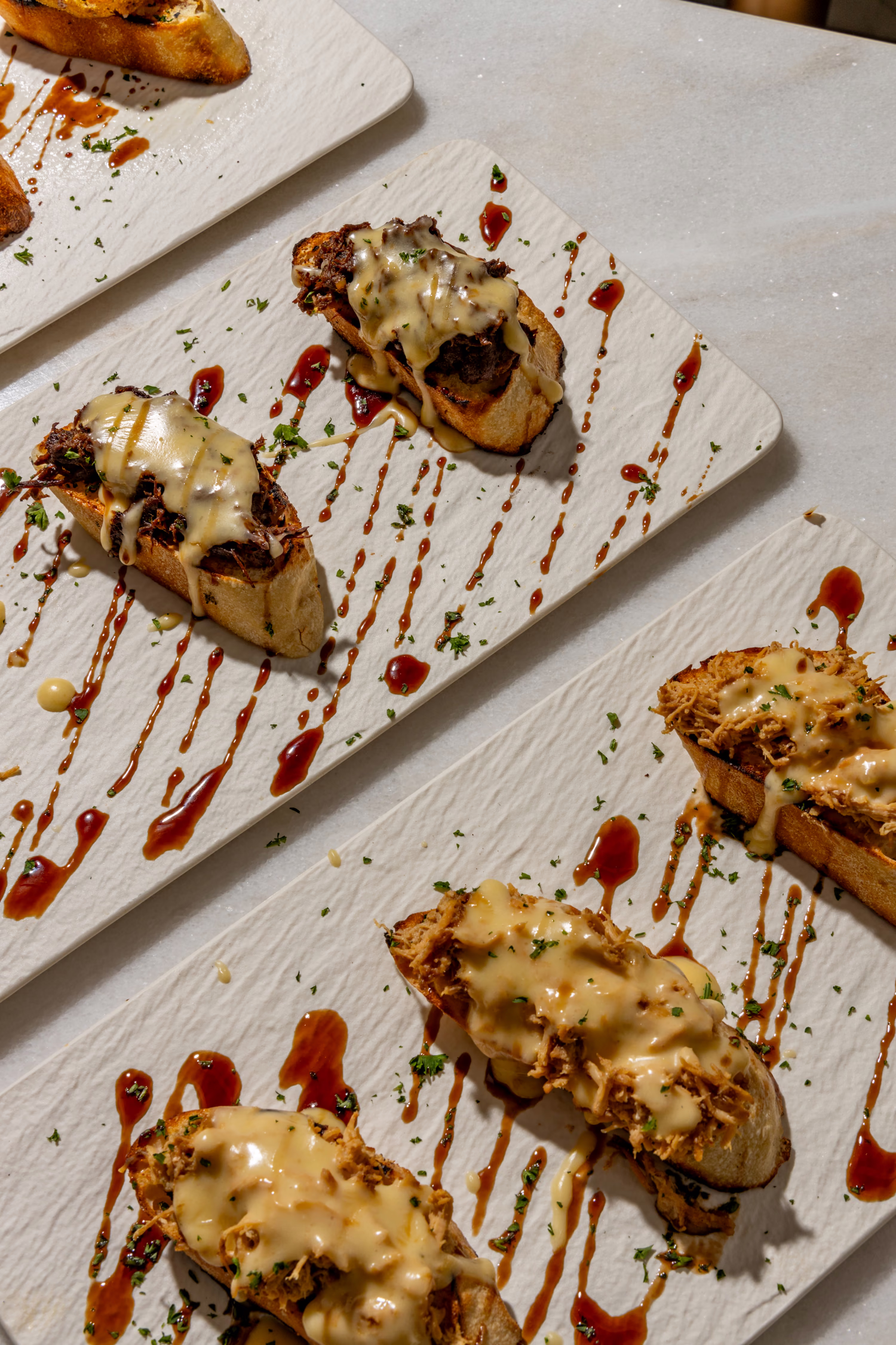 Crostini with a creamy topping on long white plates at Mistora