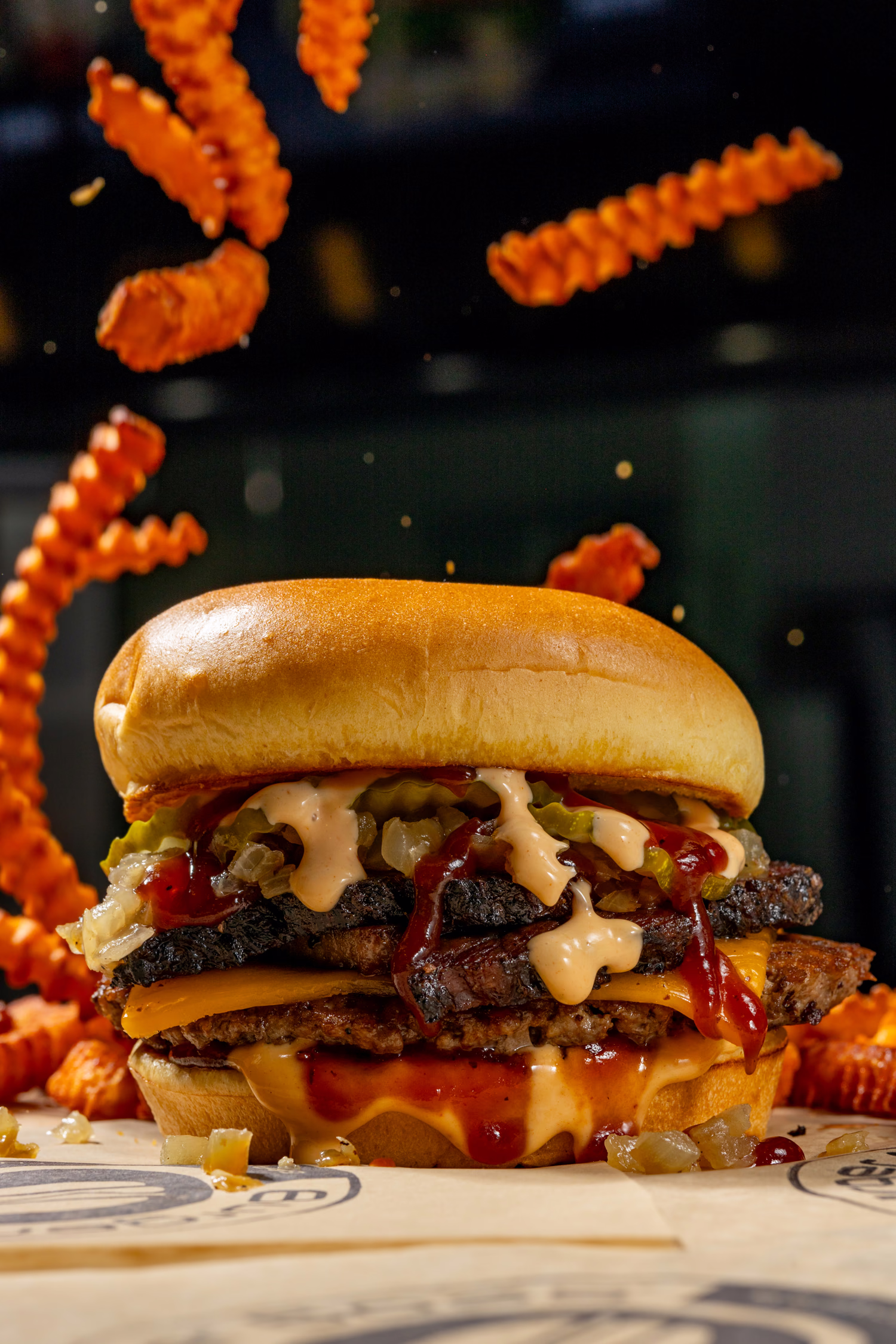 A double cheeseburger with sweet potato fries tumbling around it at Burger Boss