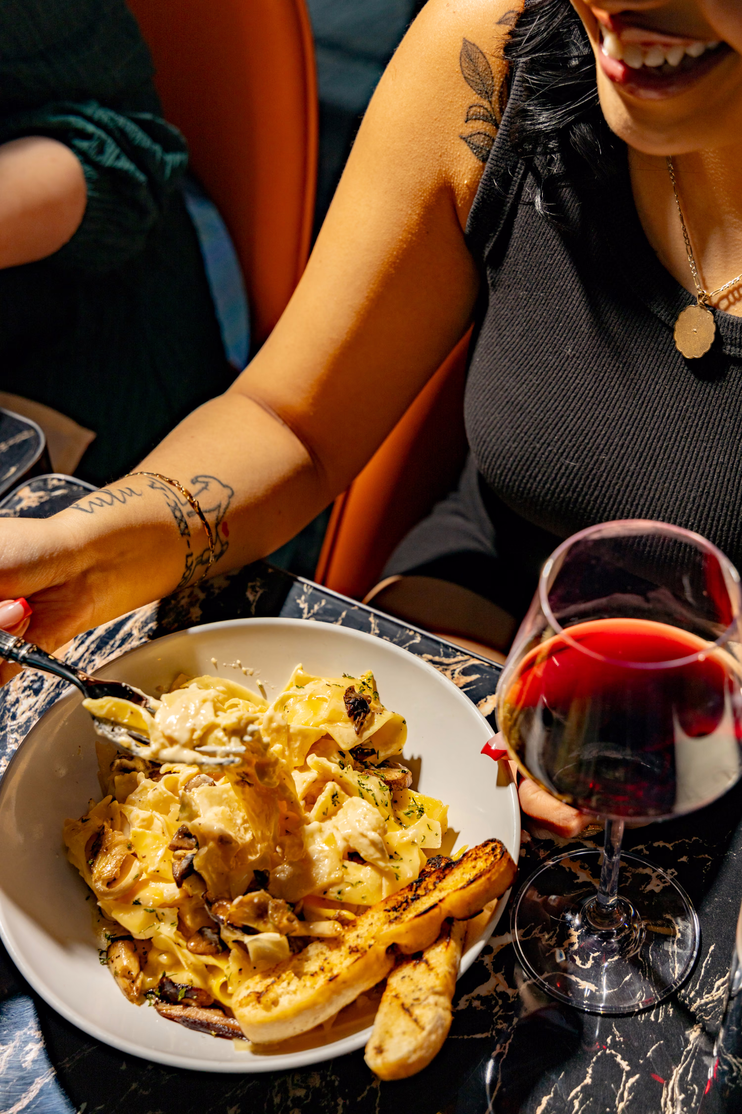 A guest serving pappardelle beside a glass of red wine at Siena