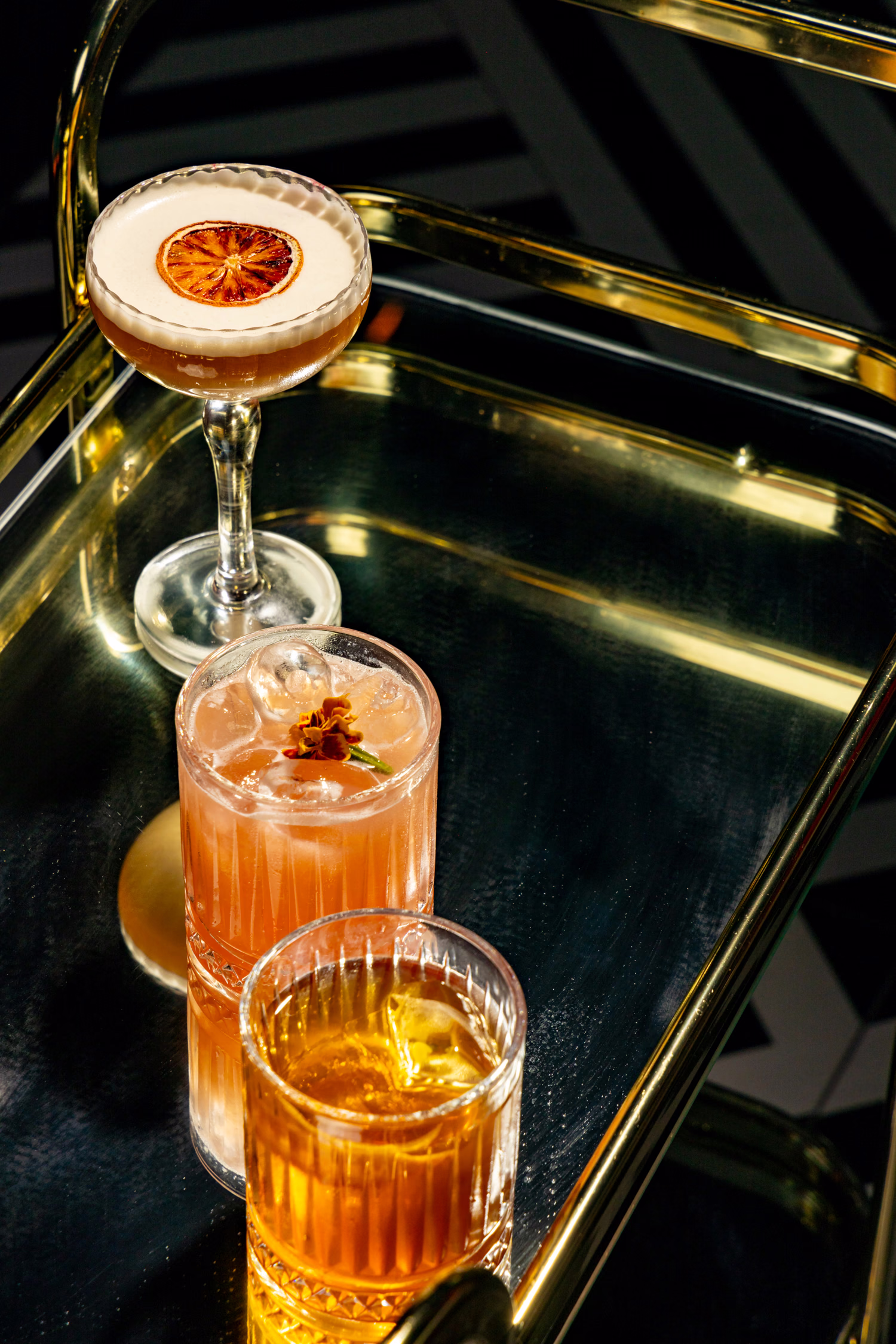 Three cocktails on a brass bar cart at Siena