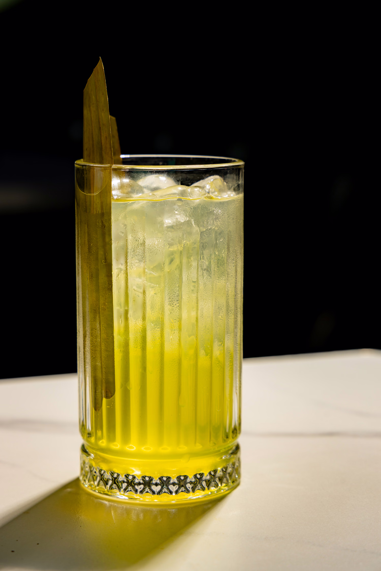 A tall pale green highball with a leaf garnish at Siena