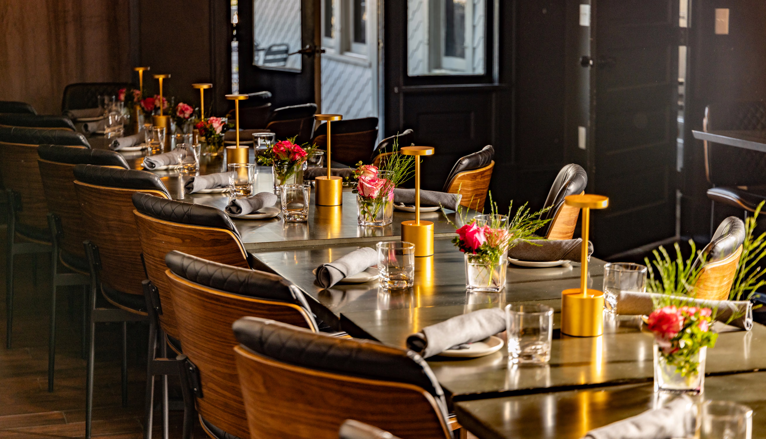 A long table set for a private dinner with gold lamps and roses at Divan