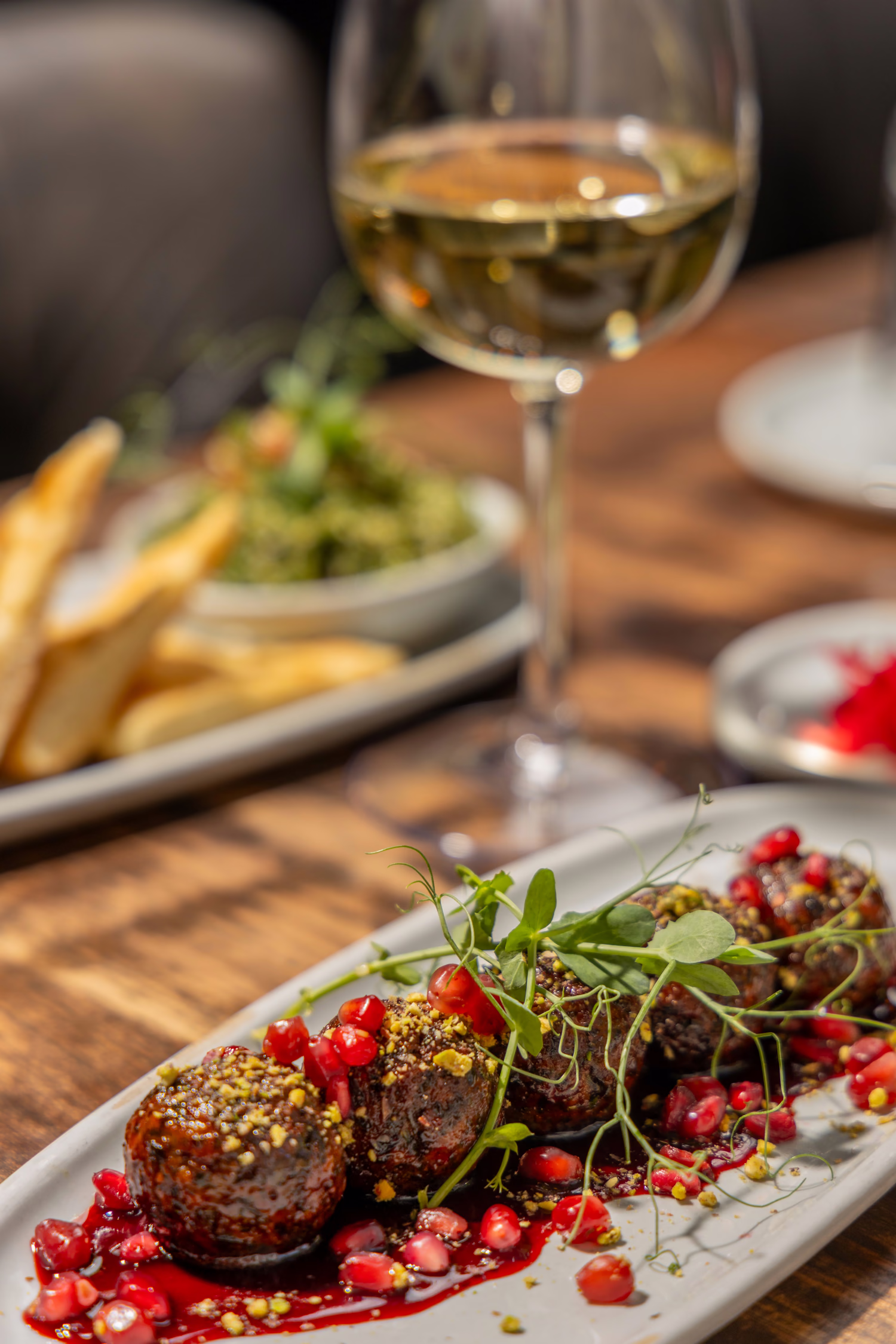 Meatballs with pomegranate and pistachio beside a glass of white wine at Divan