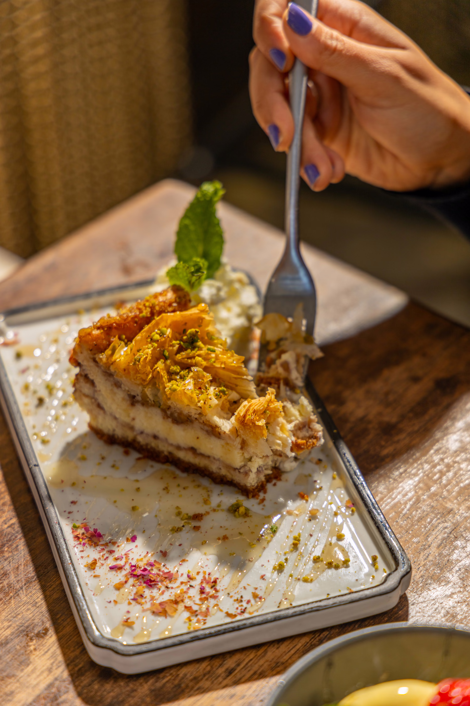 A fork cutting into a layered dessert topped with shredded pastry at Divan