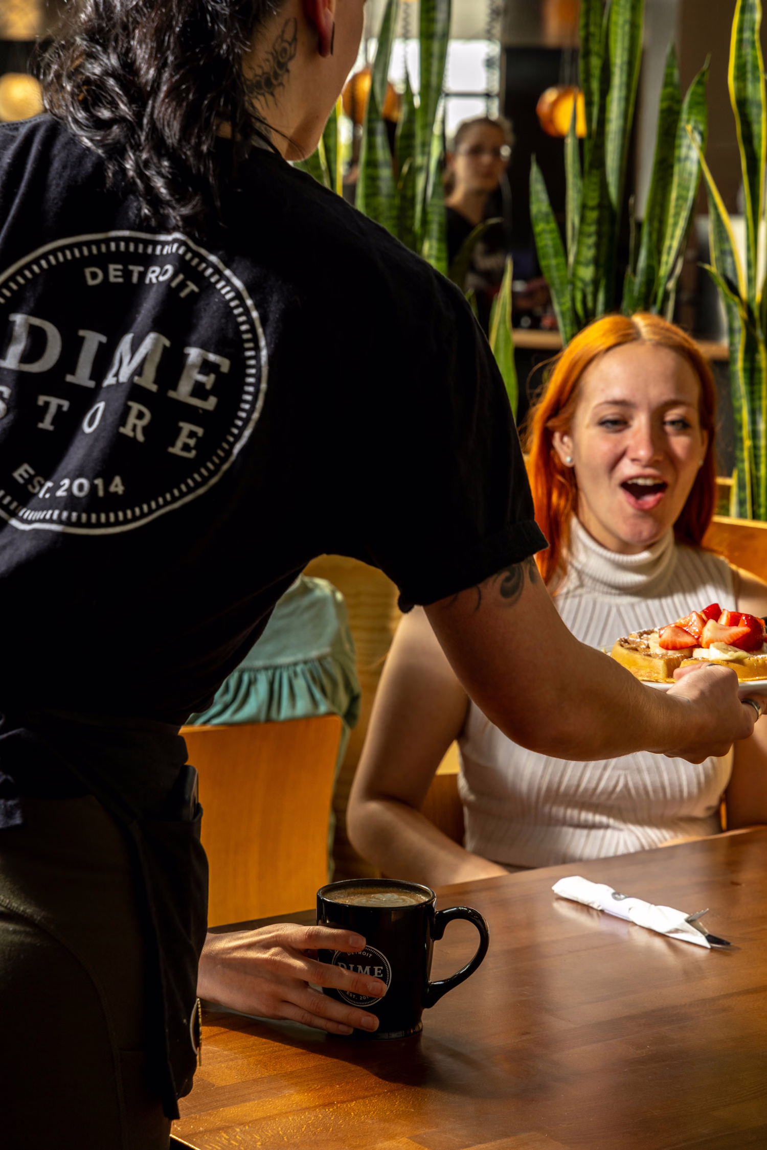A server bringing a plate to a delighted guest at Dime Store