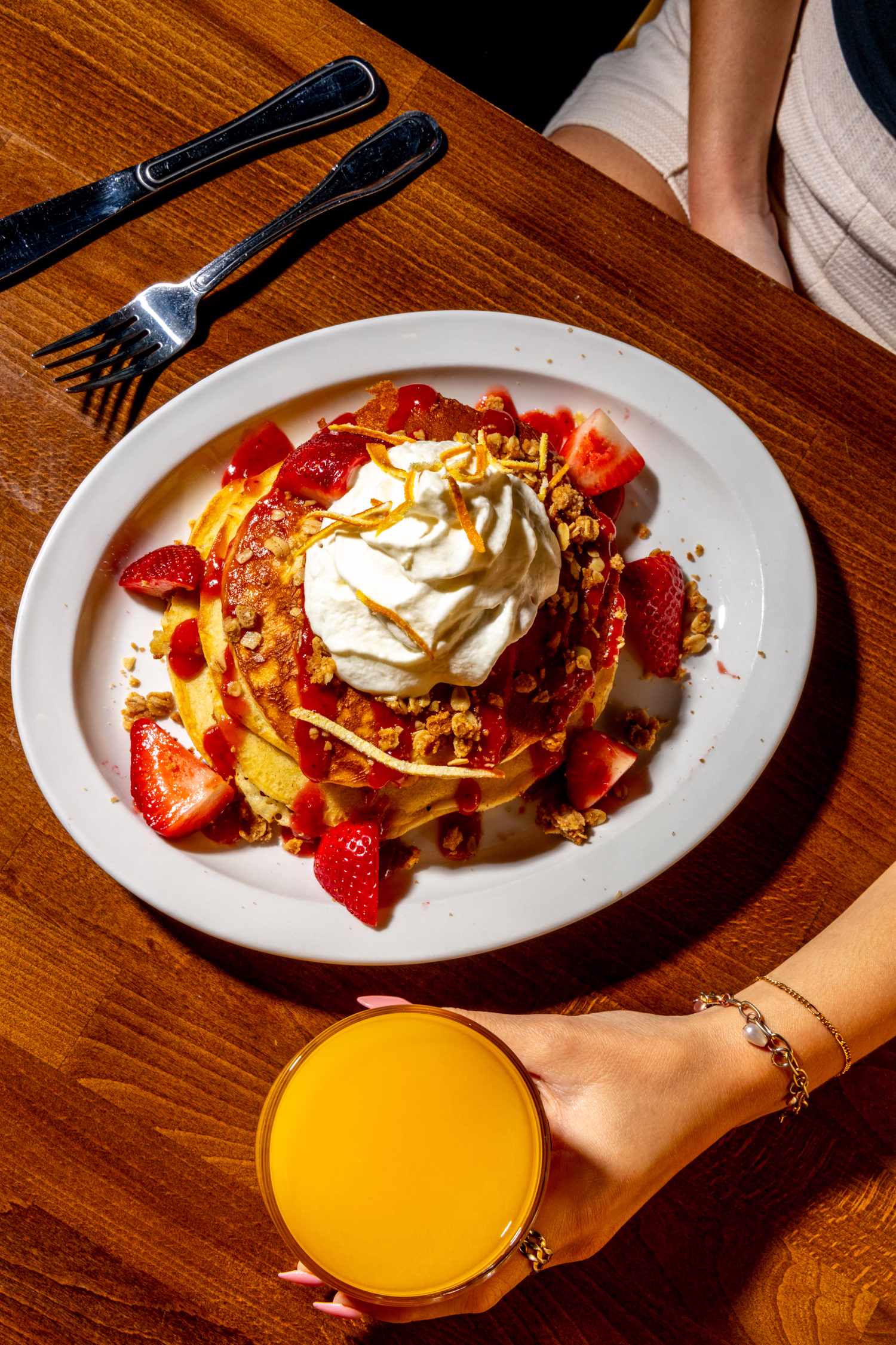 Pancakes with strawberries, whipped cream and granola seen from above at Dime Store