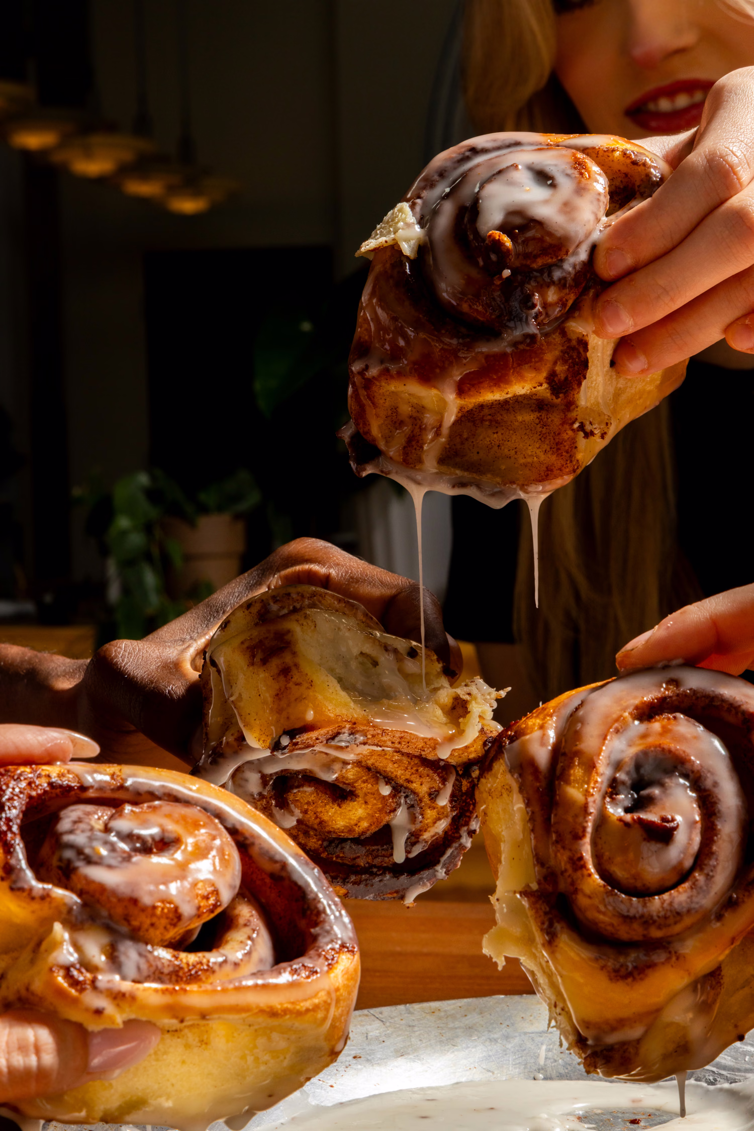 Hands pulling apart iced cinnamon rolls at Dime Store