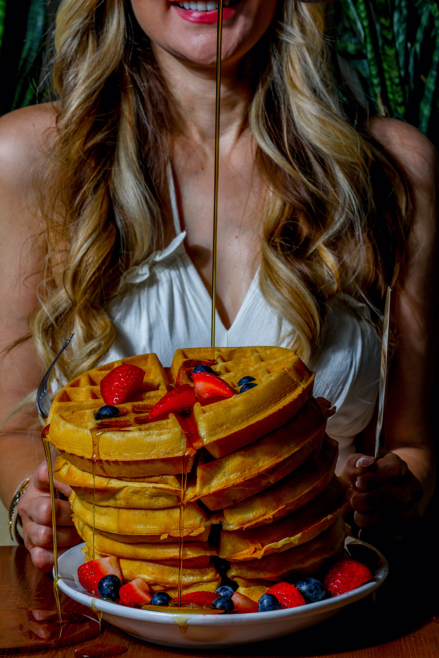 Syrup being poured over a stack of waffles with berries at Dime Store