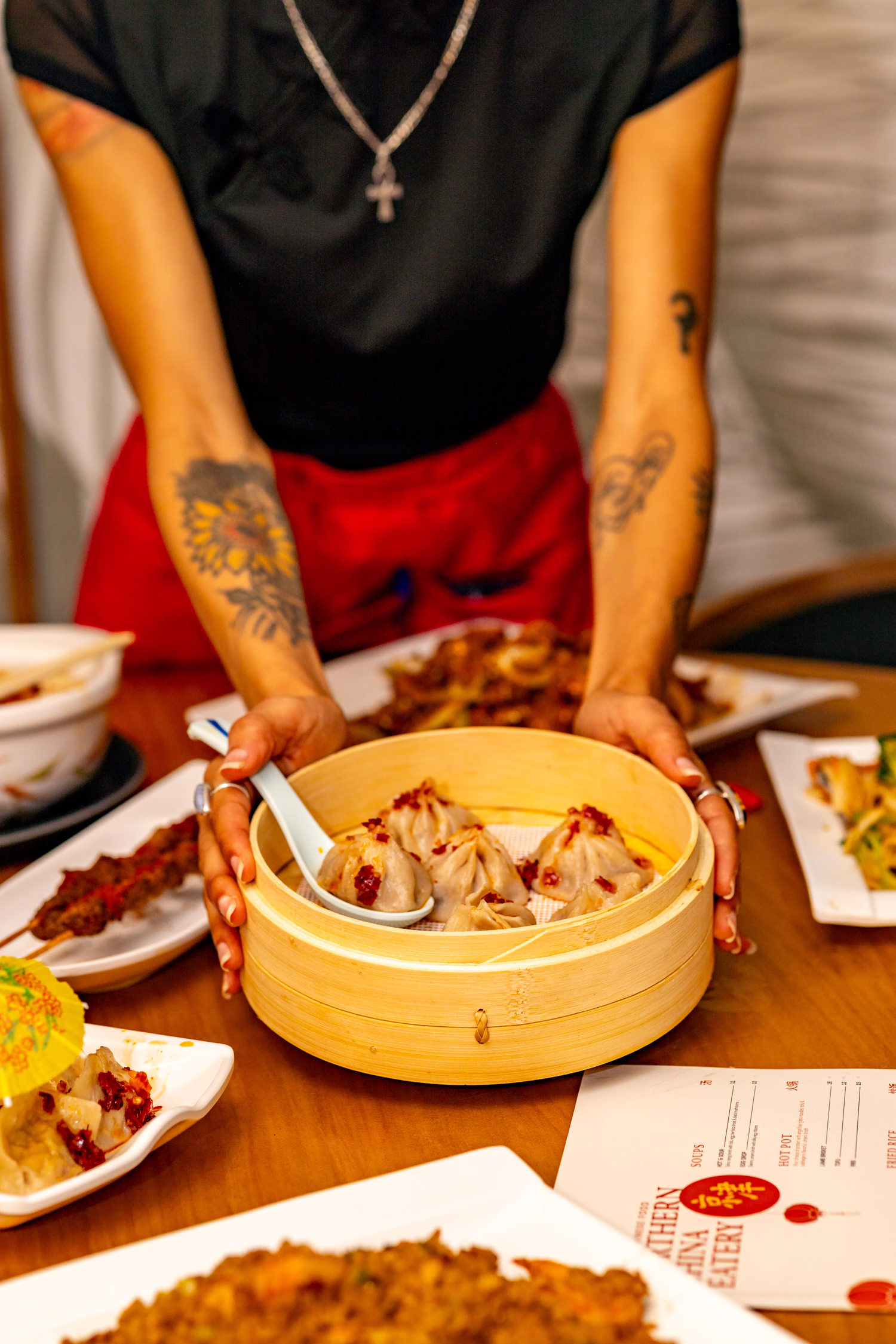 A server setting down a steamer of soup dumplings at Northern China Eatery