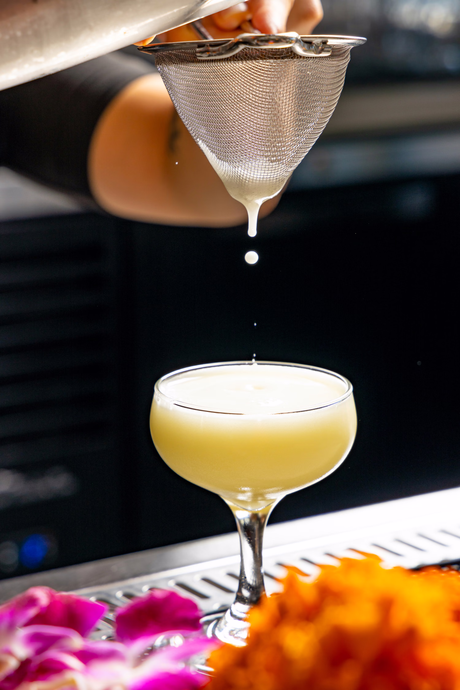 The last drop falling from a strainer into a pale cocktail at Jo's Modern Thai