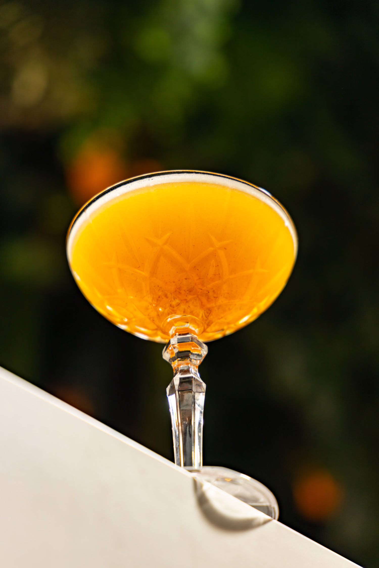 An amber cocktail in a cut-crystal coupe on a white bar at Verdure
