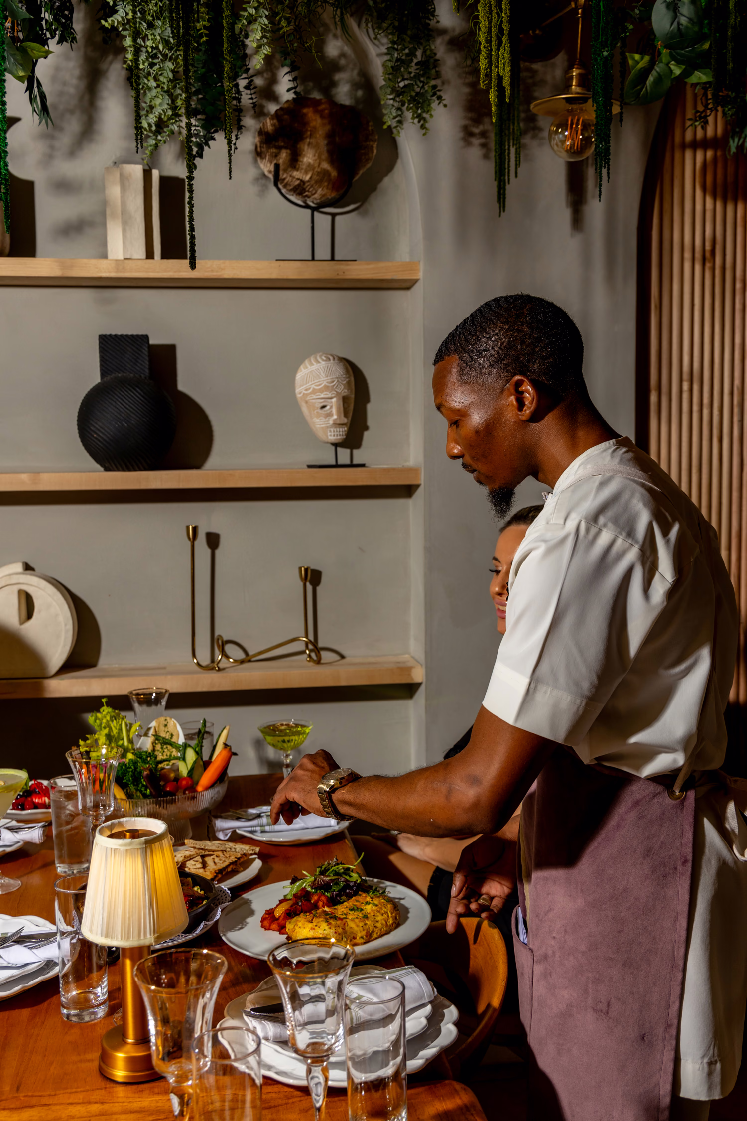 A server setting plates at a table lined with shelves of ceramics at Verdure