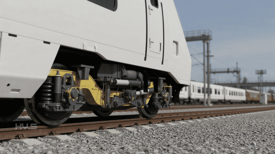 Close-up view of a modern train's wheel assembly and suspension system on railroad tracks, with a full train and electrical infrastructure visible in the background.