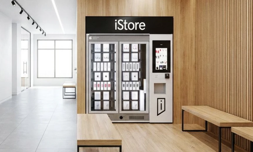 iStore electronics kiosk beside a wooden bench in a bright corridor.