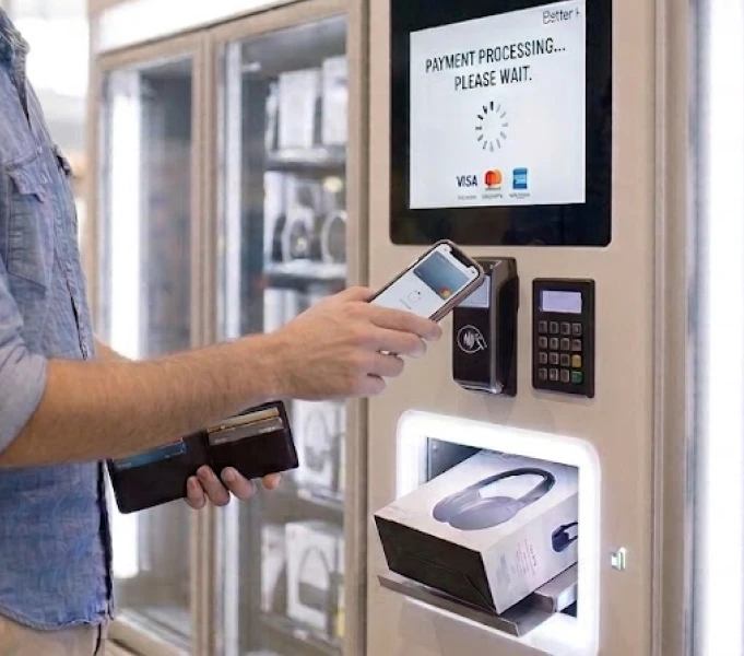 Customer using a smartphone at an automated kiosk payment reader.