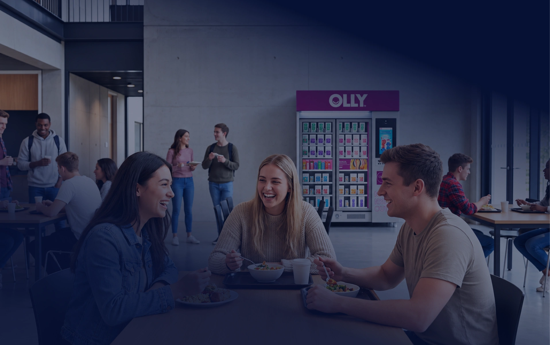 Students sitting together at a table near an OLLY kiosk.