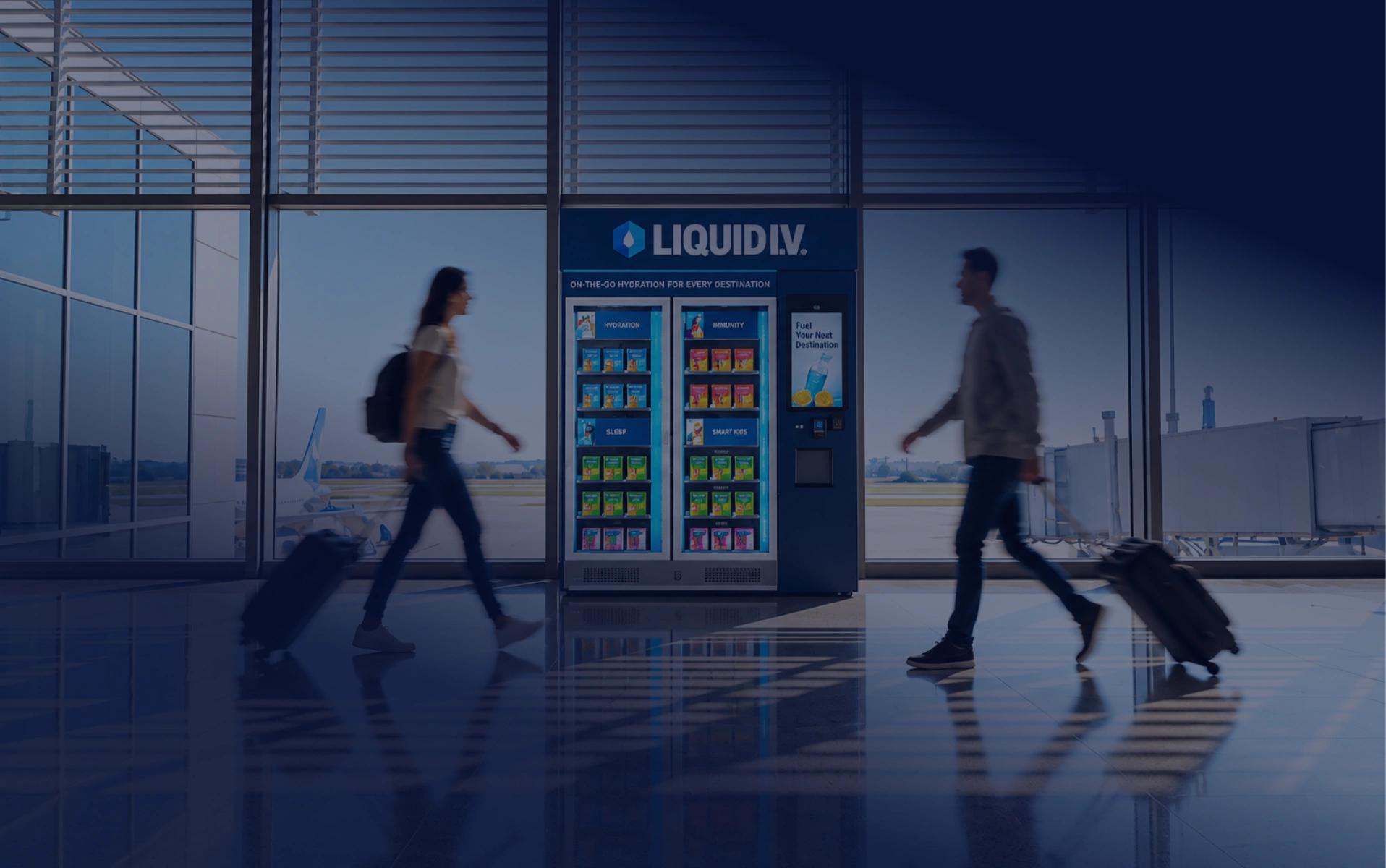 Travelers walking past a Liquid I.V. kiosk in an airport terminal.