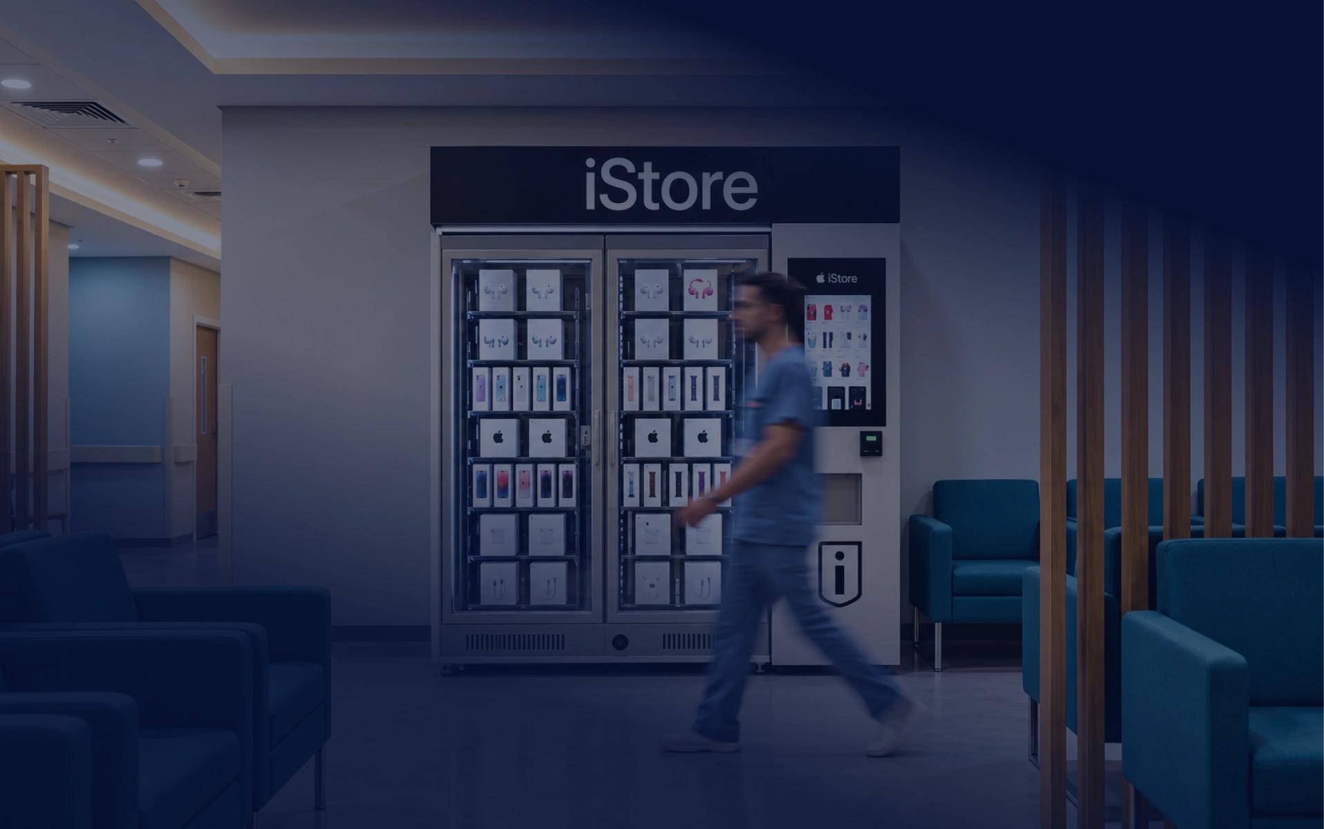 Traveler passing an iStore electronics kiosk beside lounge seating.