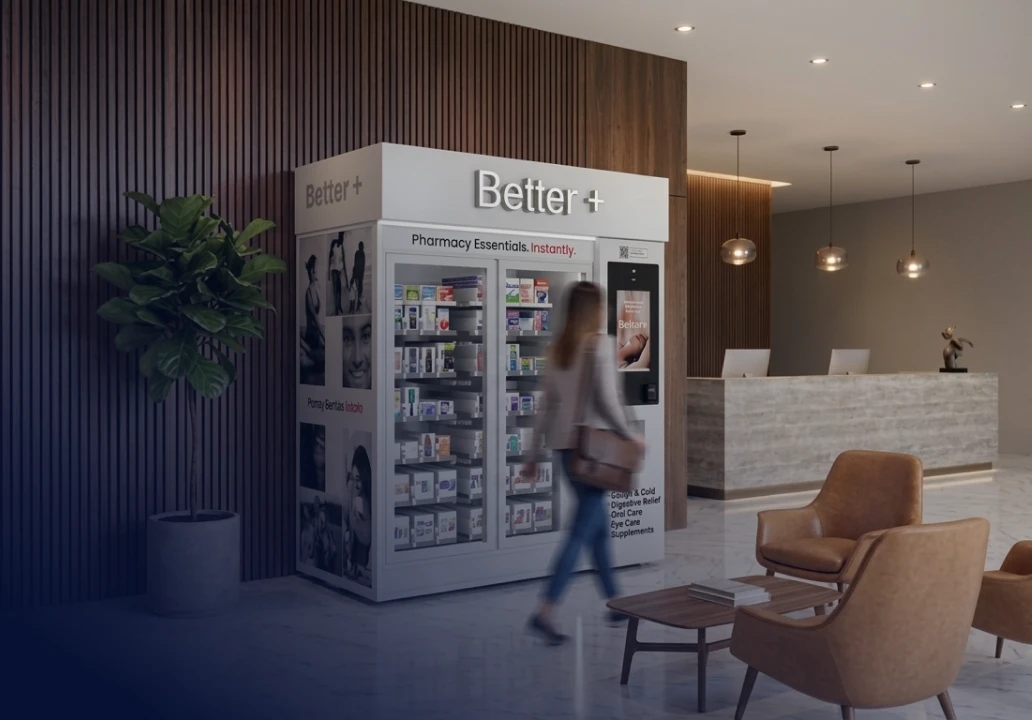 Traveler passing a Better+ kiosk beside hotel reception.
