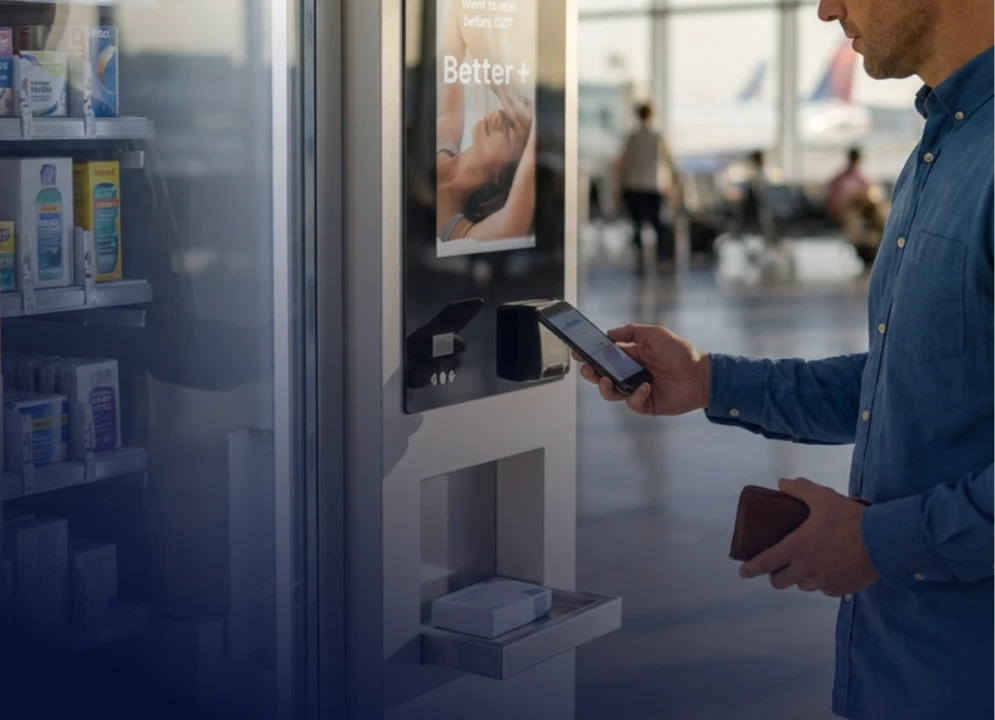 Customer holding a smartphone near a kiosk payment reader.