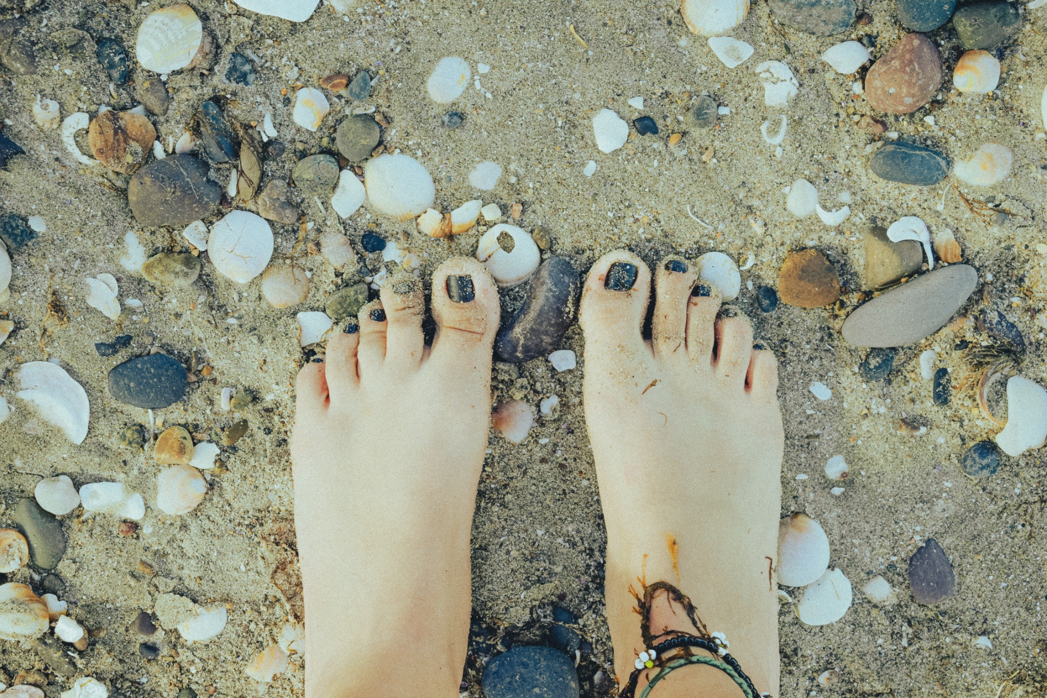 Bare feet in clear water on a pebbled beach