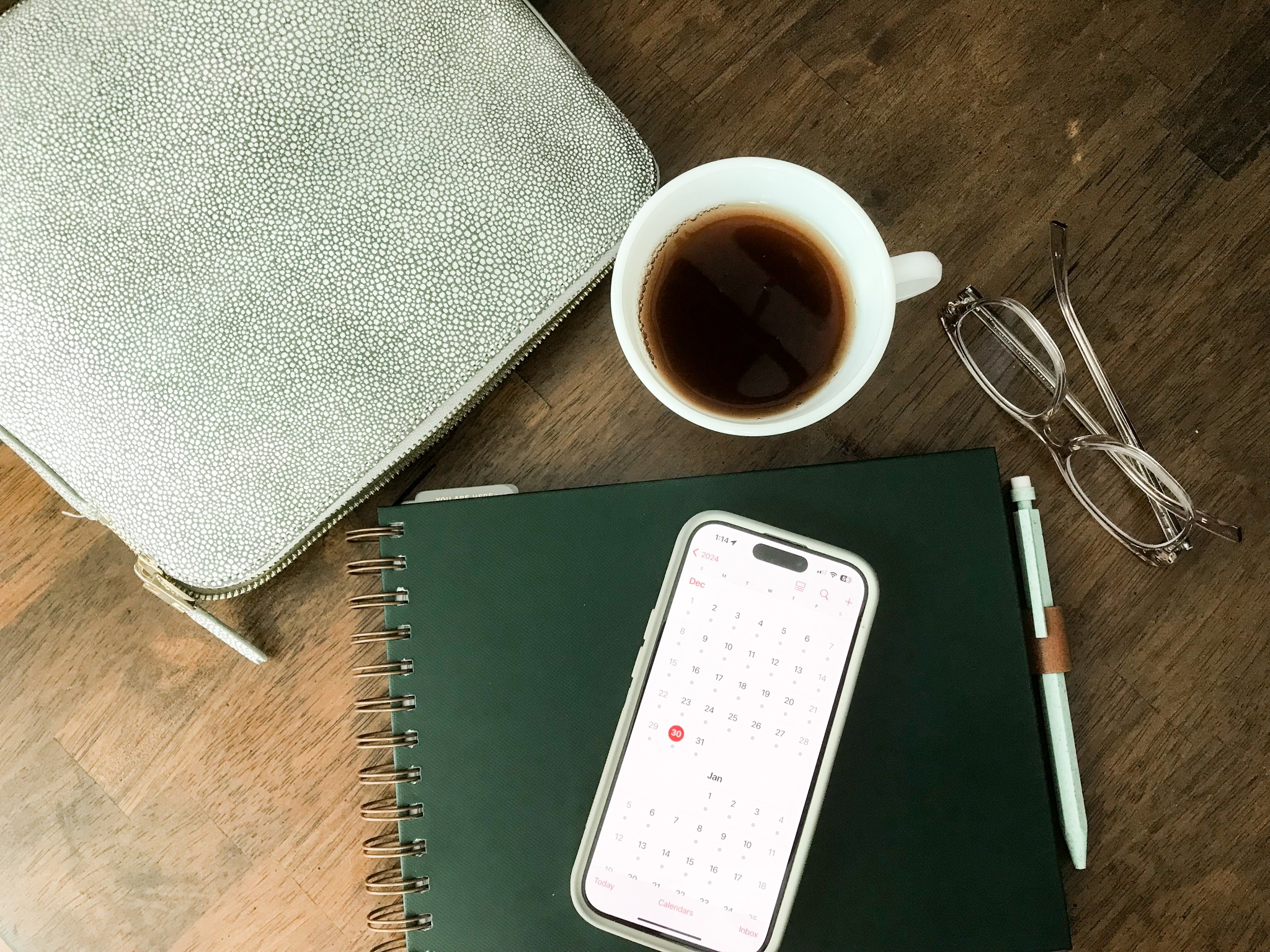 Coffee, glasses, a notebook and a phone calendar on a wooden table
