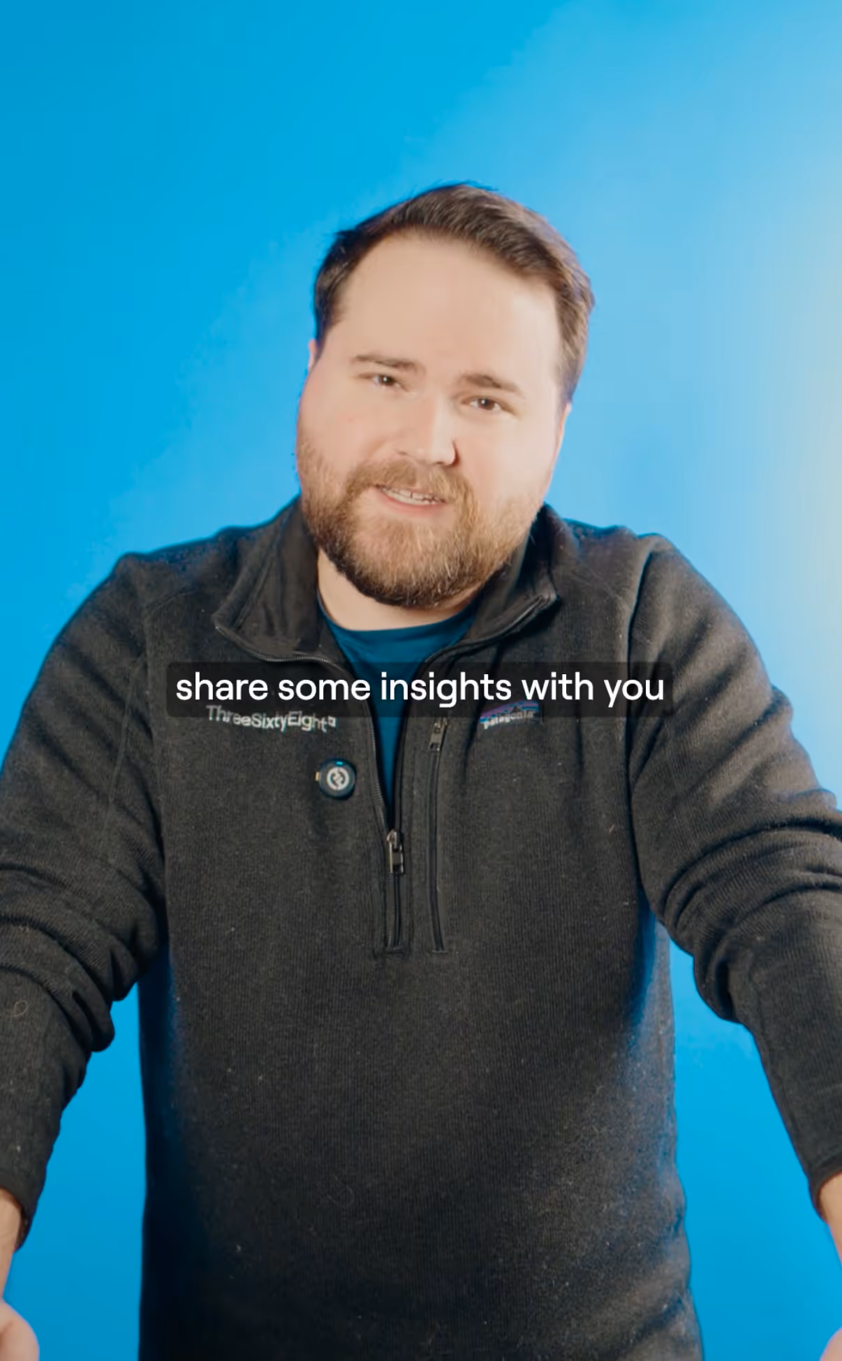 Bearded man in a black zip-up sweater speaking against a bright blue background with the caption 'share some insights with you.'
