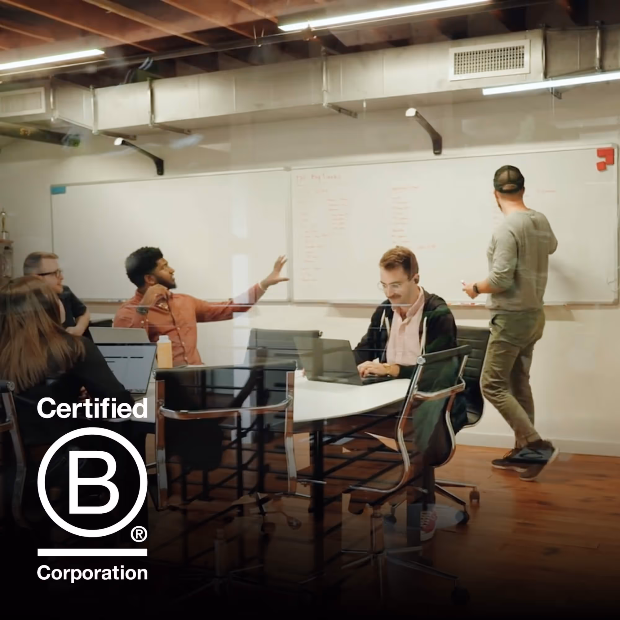 TSE team workshopping on the white board in the conference room. Overlaid is the "Certified B Corporation" logo.