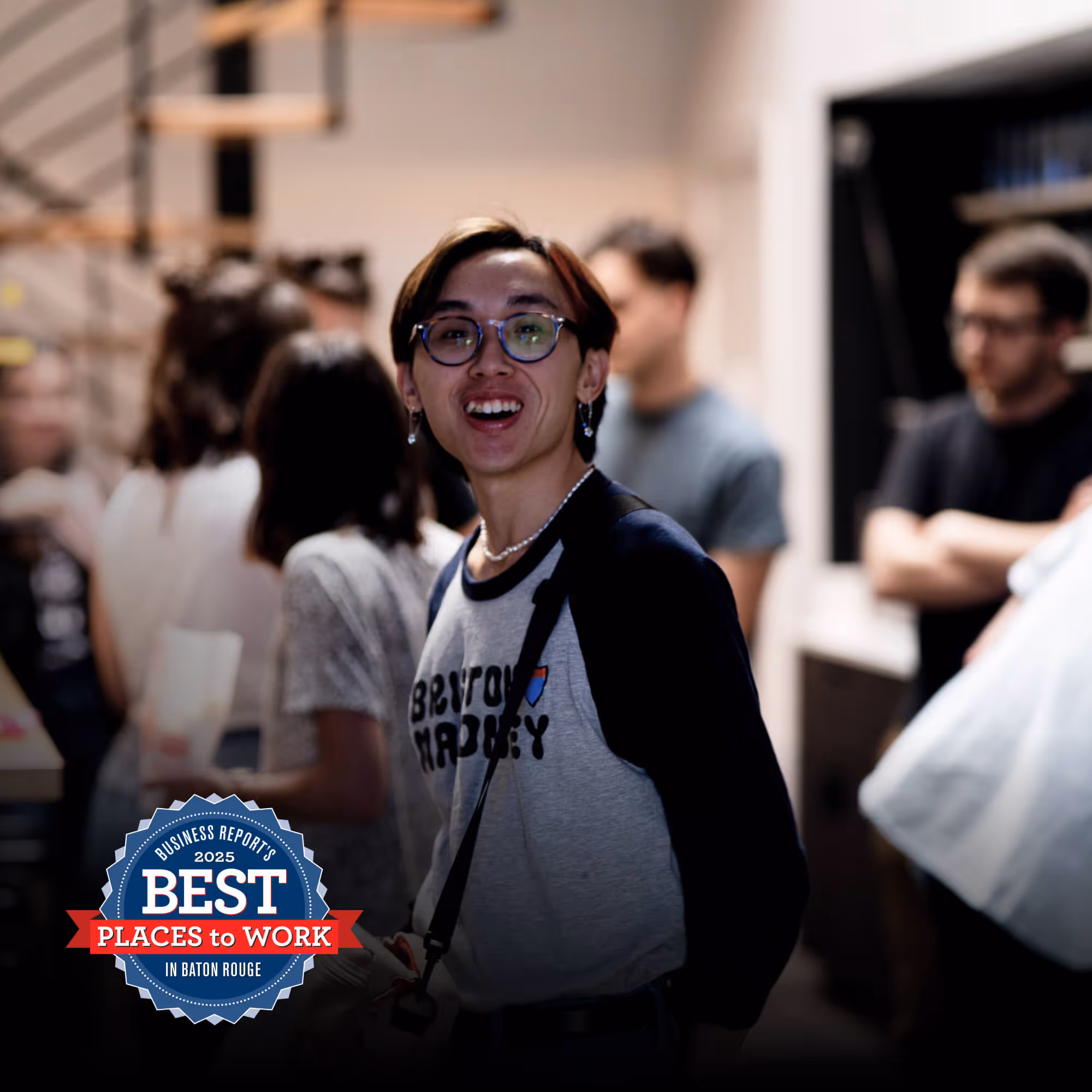 Picture of TSE member, Khoi, smiling in the TSE kitchen. Best Places to Work logo overlaid on the image.