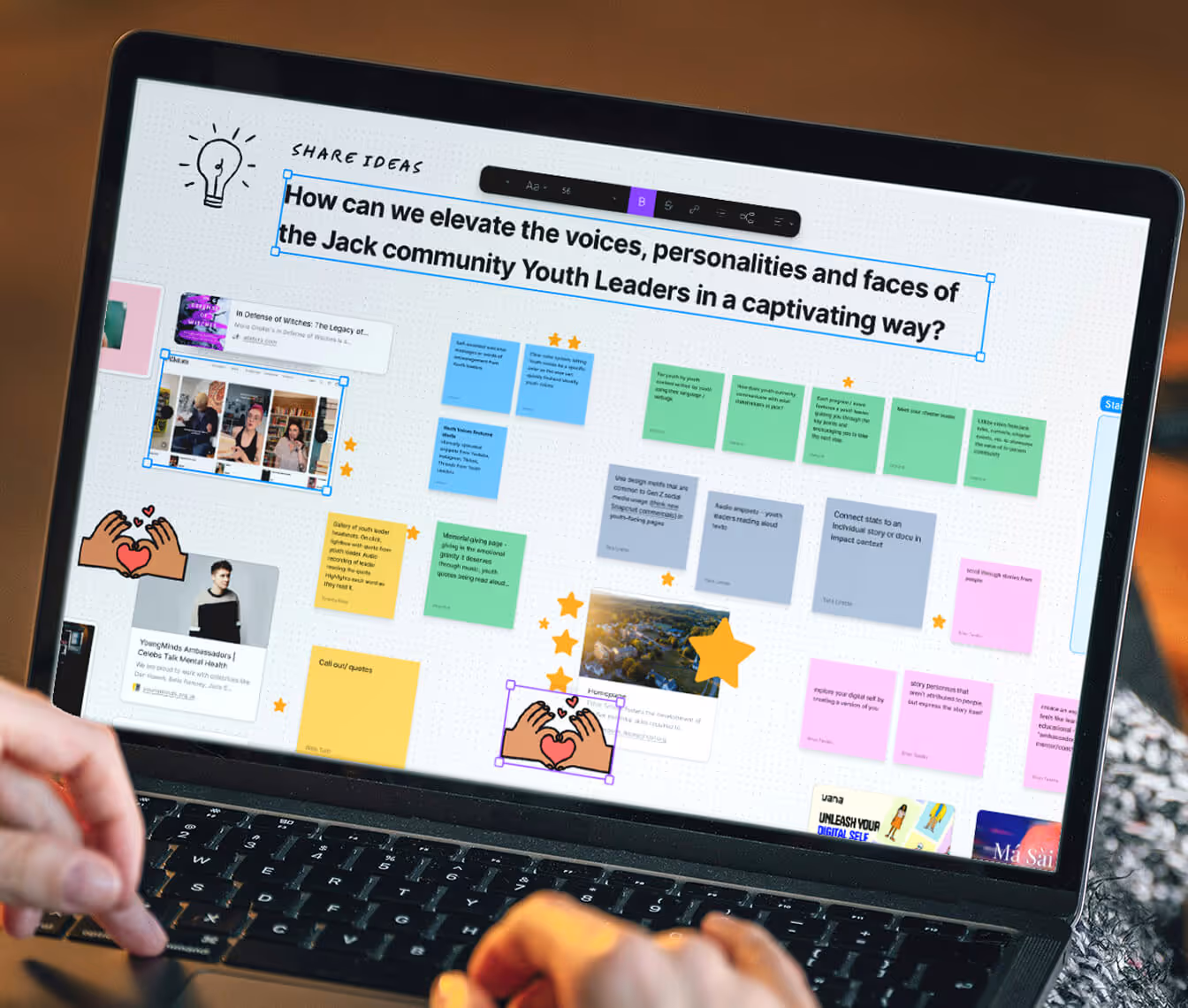 Laptop screen showing a digital whiteboard with the question 'How can we elevate the voices, personalities and faces of the Jack community Youth Leaders in a captivating way?' surrounded by colorful sticky notes, images, and hand heart emojis.