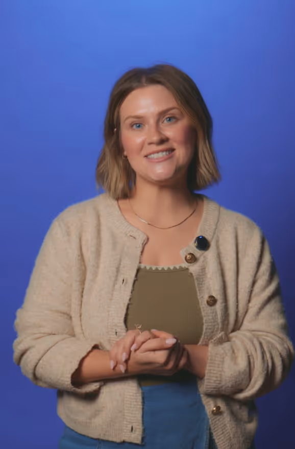 Kelsey wearing a beige cardigan and green top against a blue background.