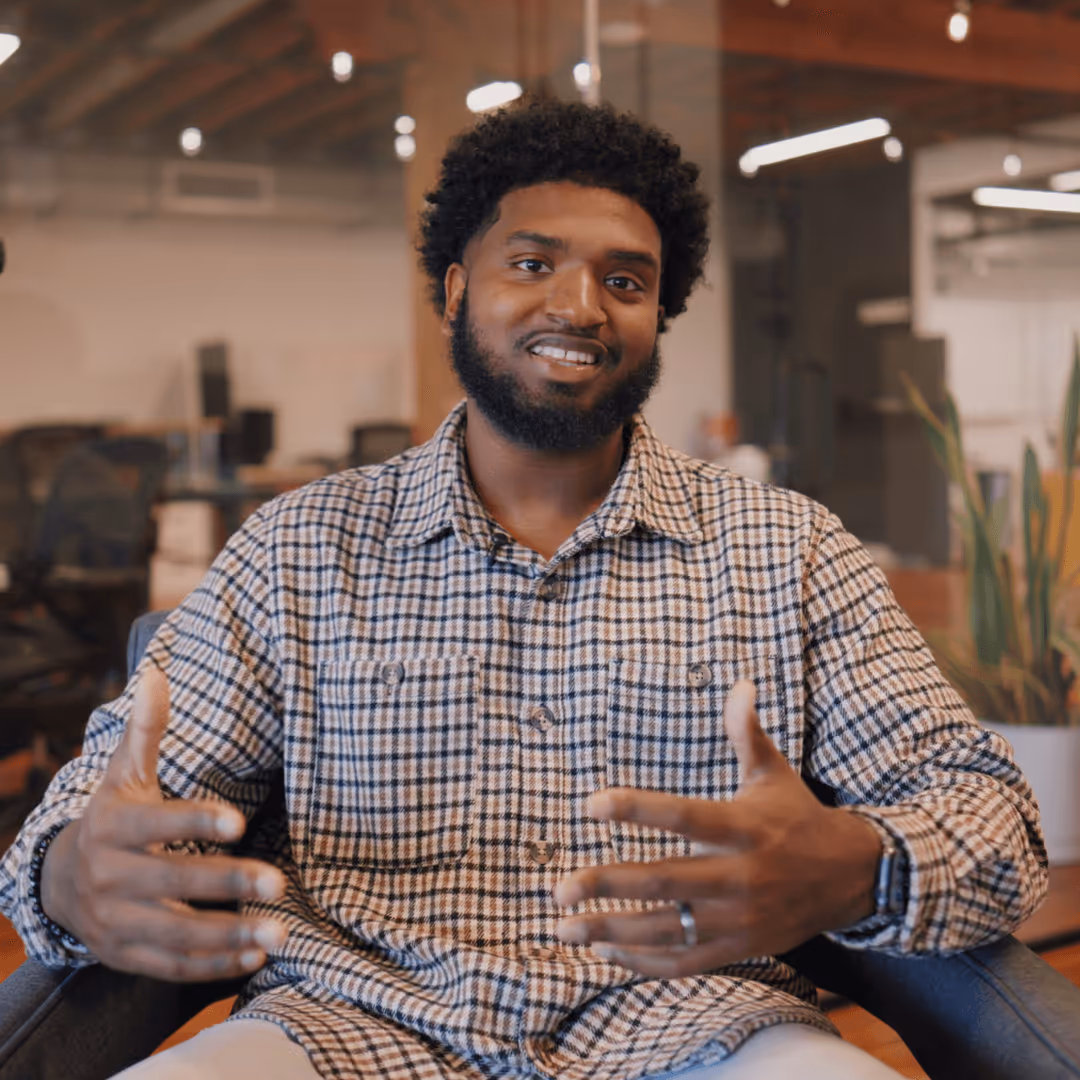 Smiling man wearing a checkered shirt with text overlay saying 'Thanks for reaching out to us' in an office setting.