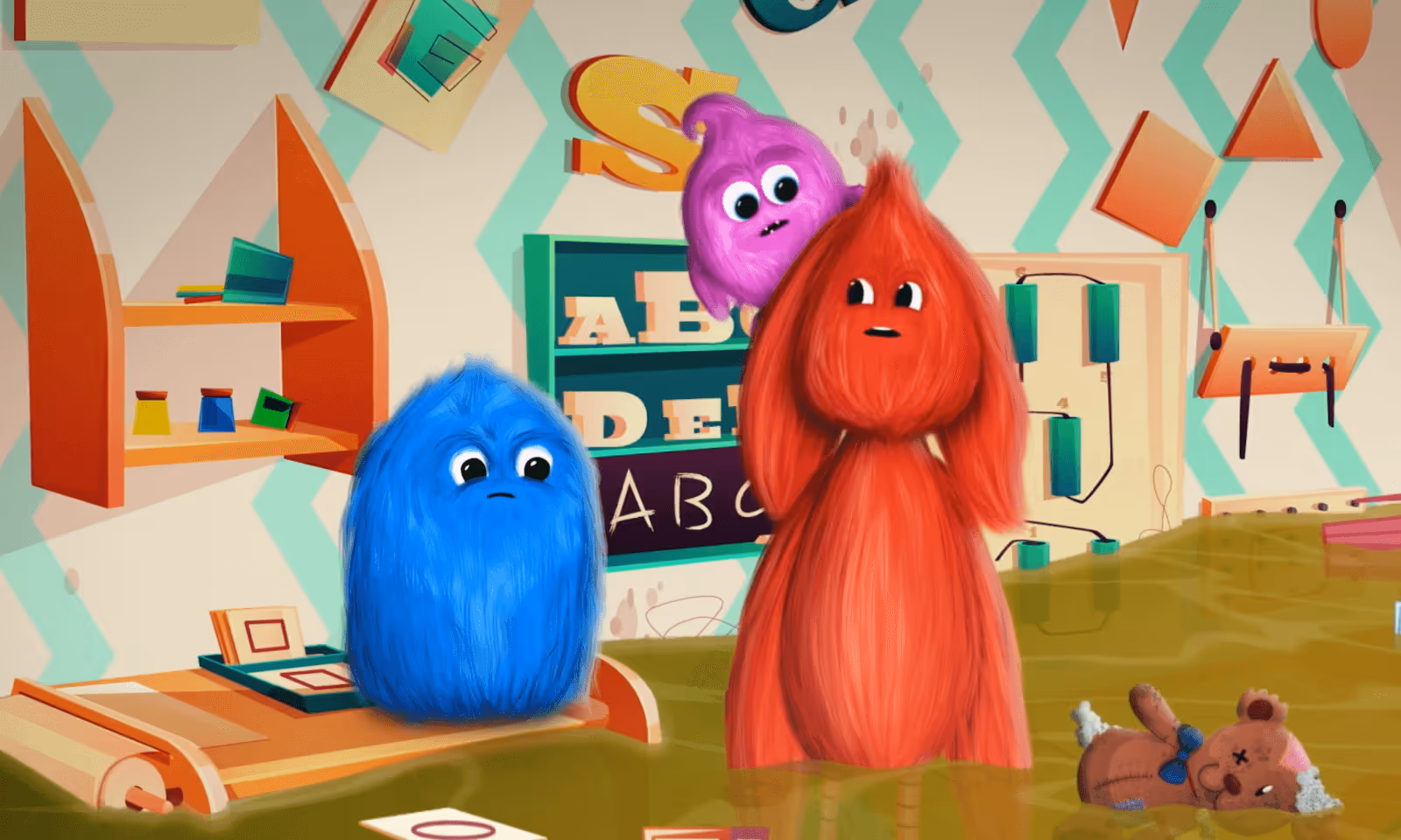 Three colorful furry cartoon creatures in a playful classroom with alphabet decorations and a teddy bear on the floor.