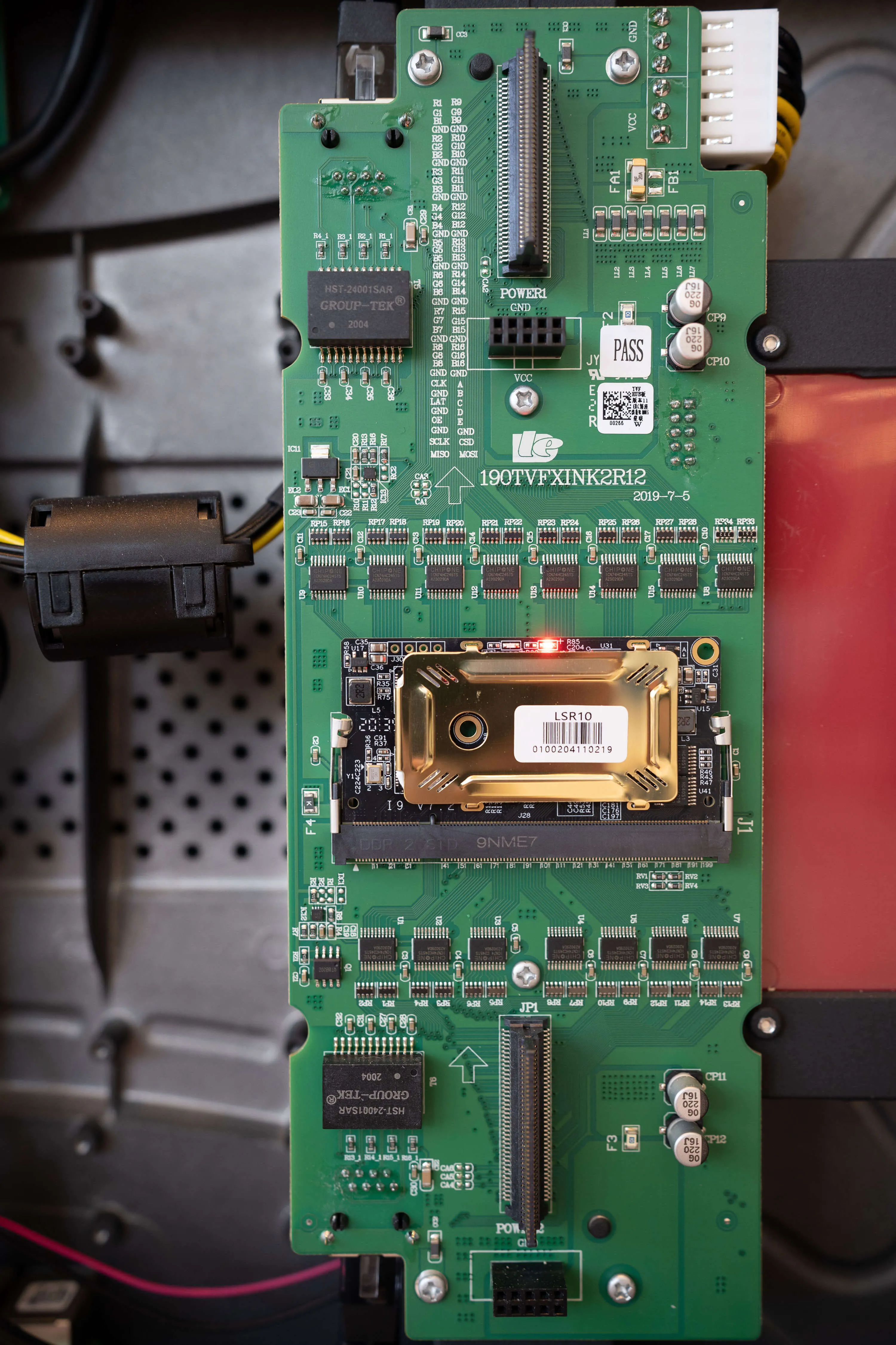 Close-up of a green circuit board with various integrated chips, connectors, and electronic components mounted on it.