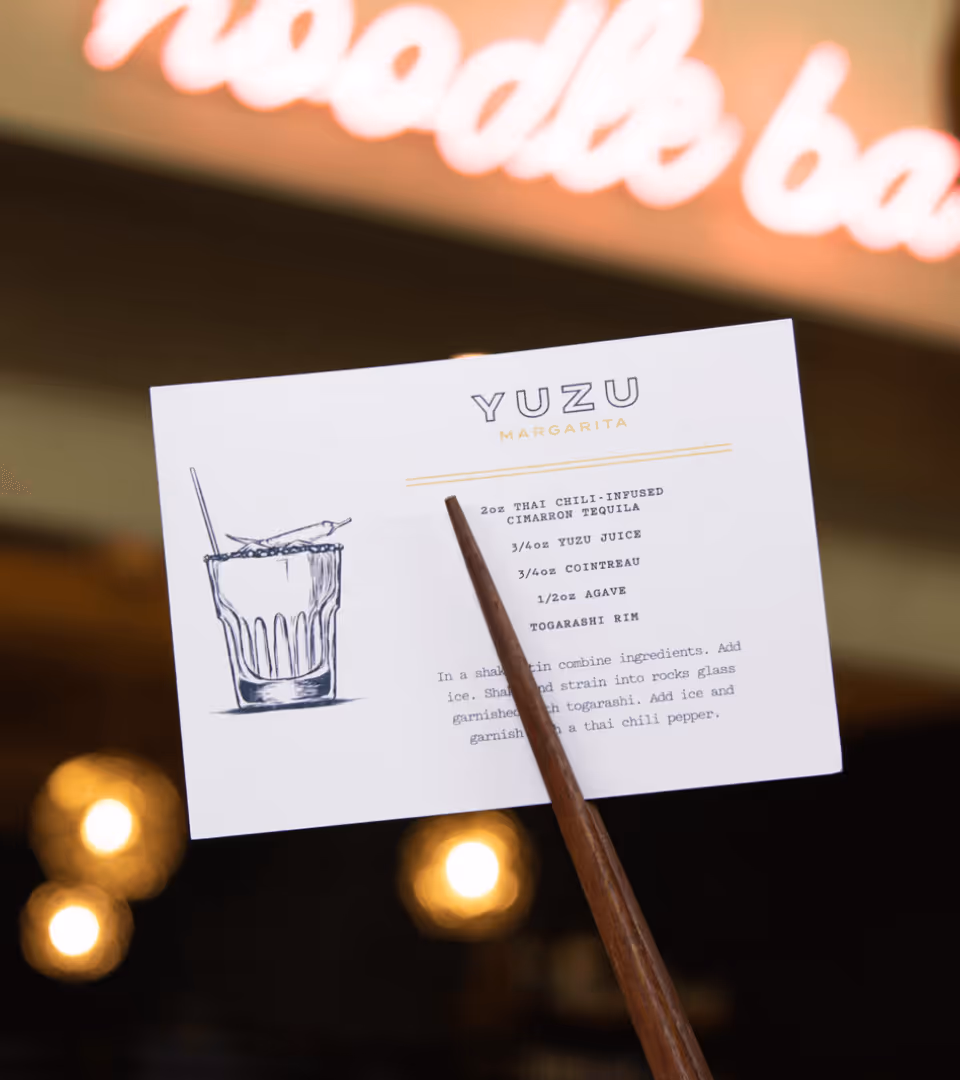 Cocktail recipe card for Yuzu Margarita held by chopsticks with illustrated glass and ingredients listed.