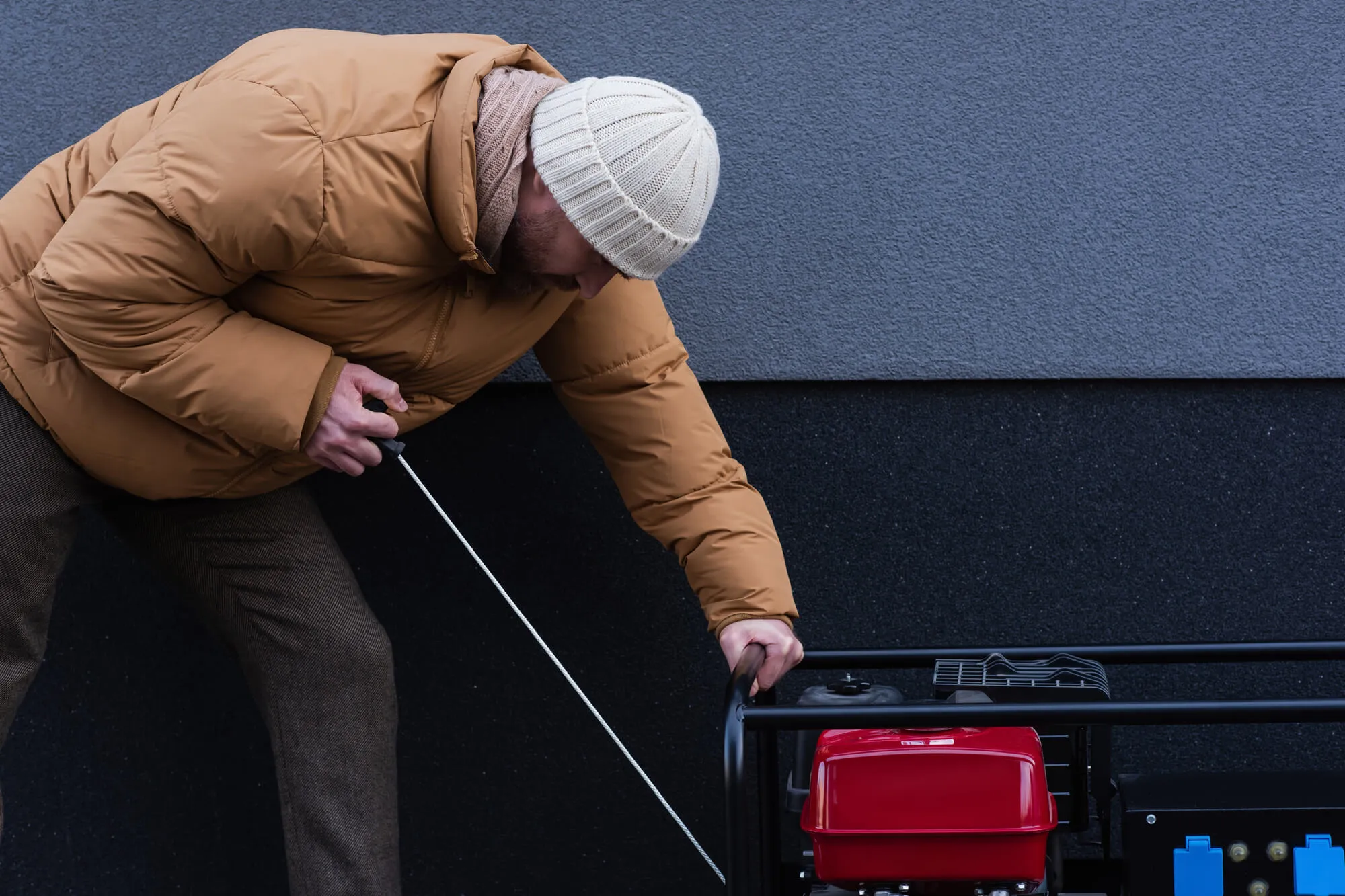 Homeowner pulling the start cord on a portable generator