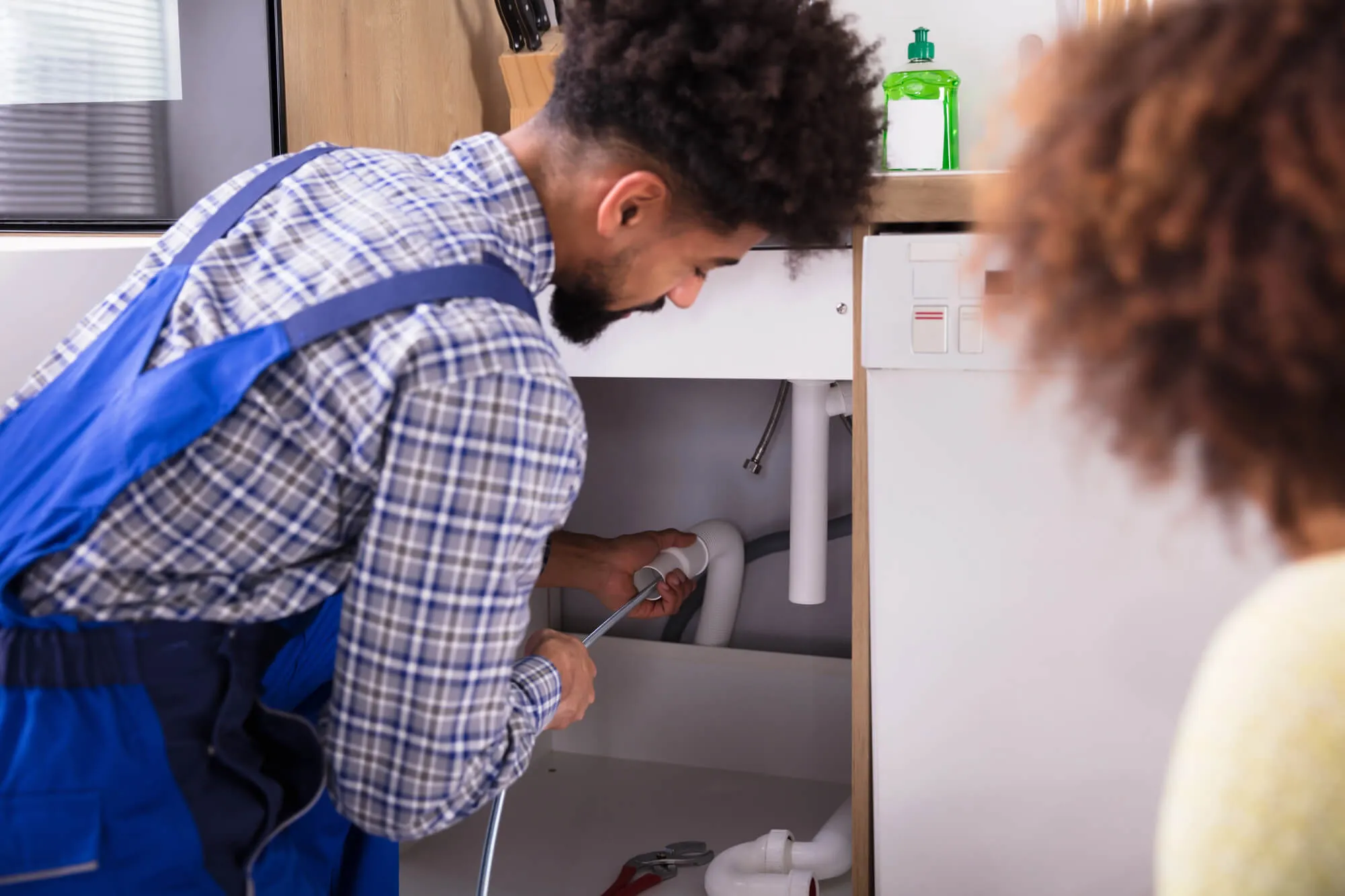 Plumber inspecting the pipes under a kitchen sink
