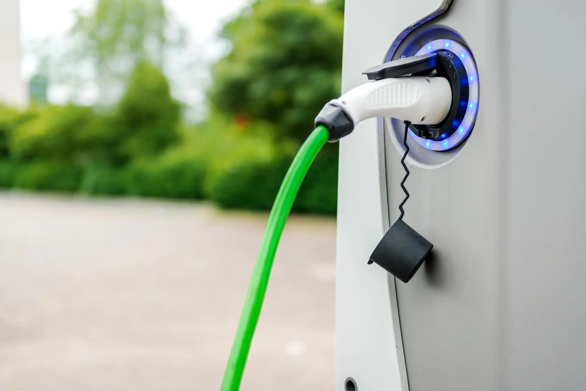 Electric vehicle charger plugged in at a charging station