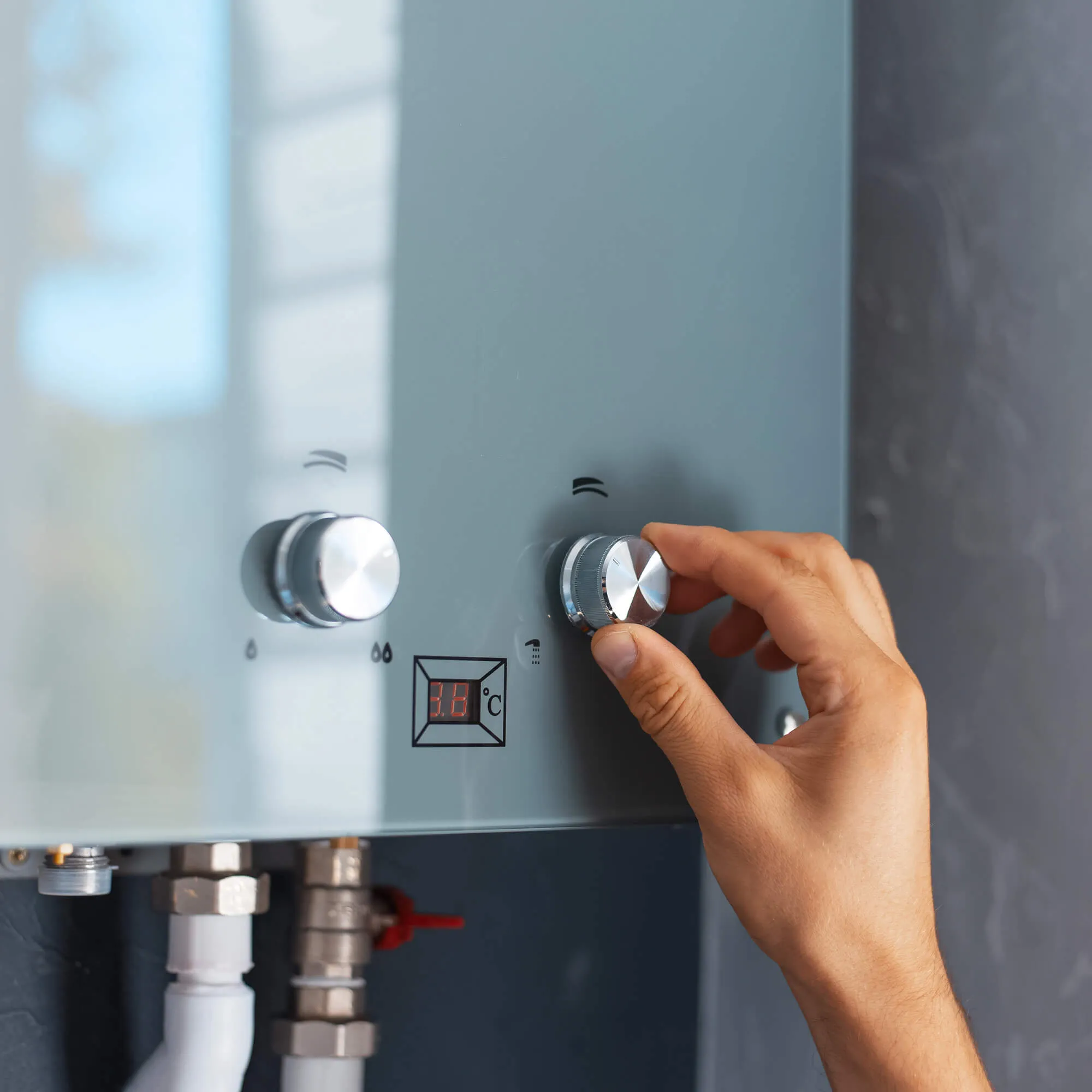 Hand adjusting the controls on a tankless water heater
