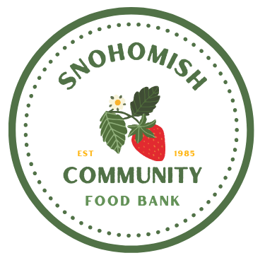 Circular logo featuring a red strawberry with green leaves and a white flower in the center, surrounded by the text 'Snohomish Community Food Bank' and 'Est 1985'.