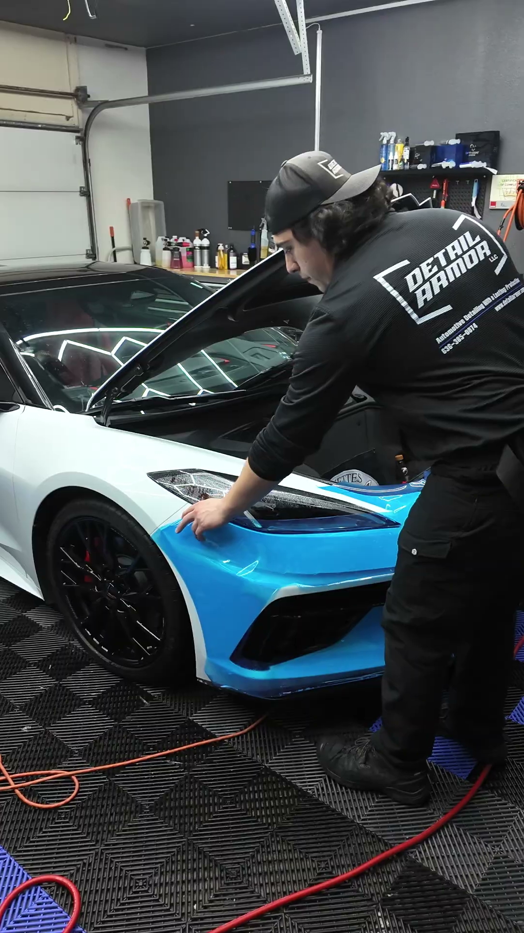 Gavin installing paint protection film on the front bumper of a white C8 Corvette