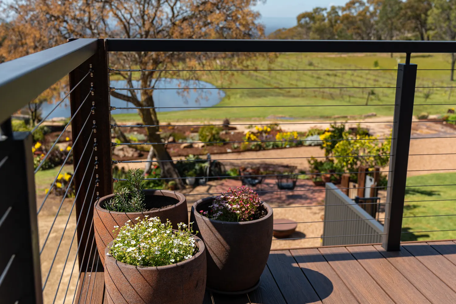 The balcony rail, looking past the potted plants over the dam and the vineyard