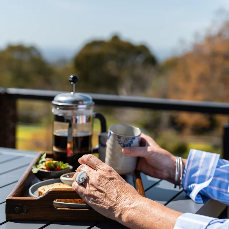 A coffee plunger and breakfast on the balcony rail, with the view beyond
